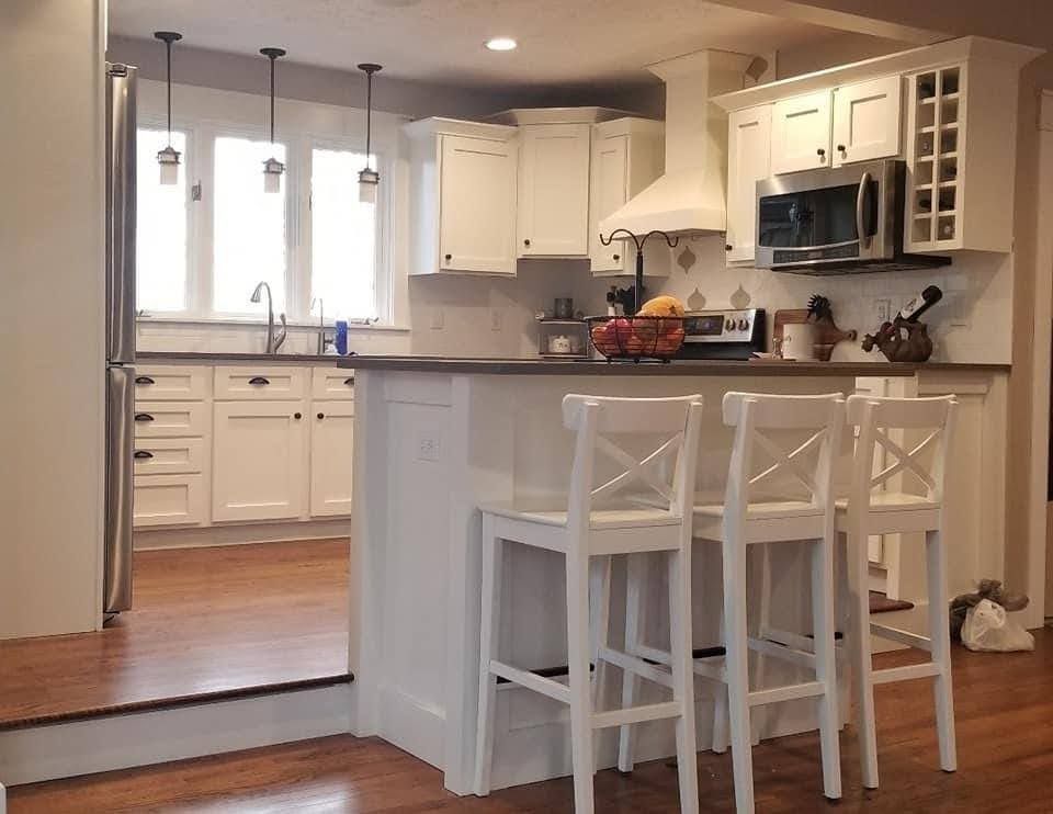 Bright white kitchen with island seating, stainless appliances, and hardwood floors
