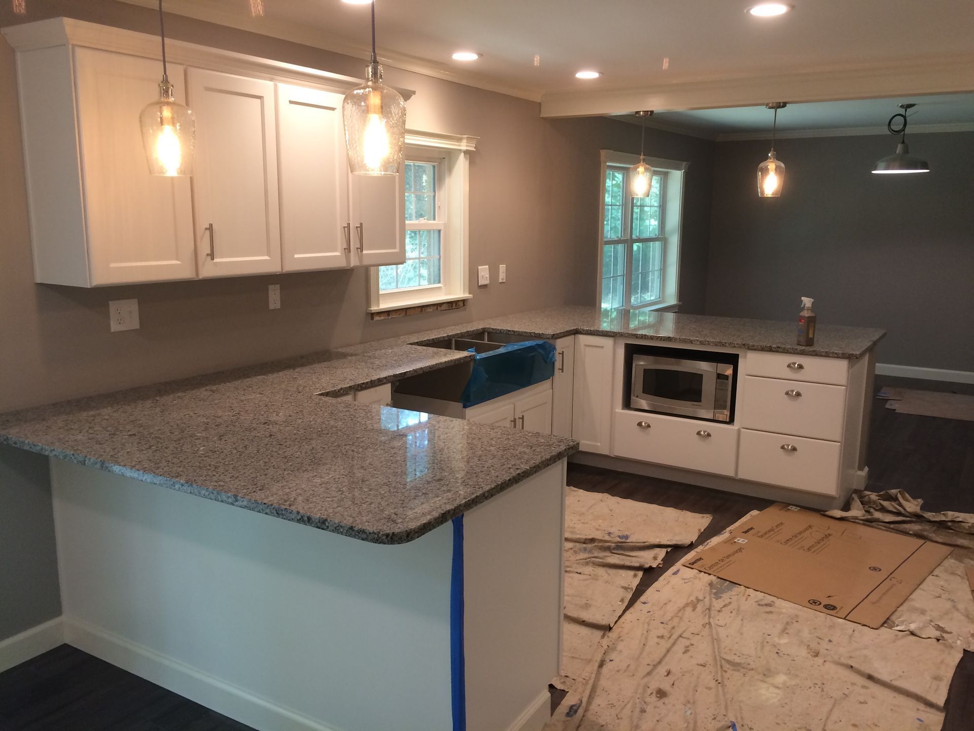Partially remodeled kitchen with white cabinets, gray countertops, and unfinished flooring
