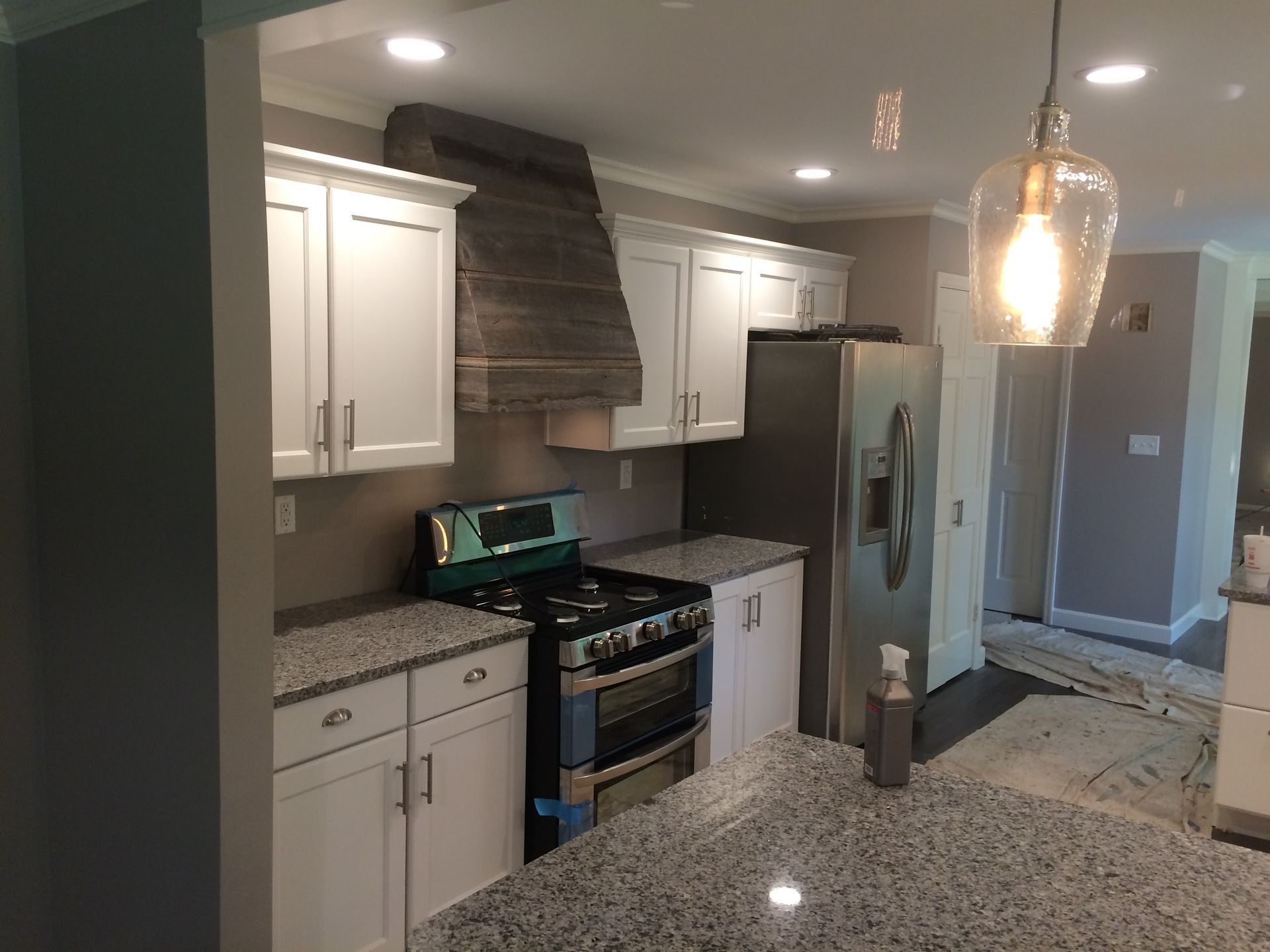 Modern kitchen with white cabinets, granite counters, stainless fridge, and patterned tile backsplash