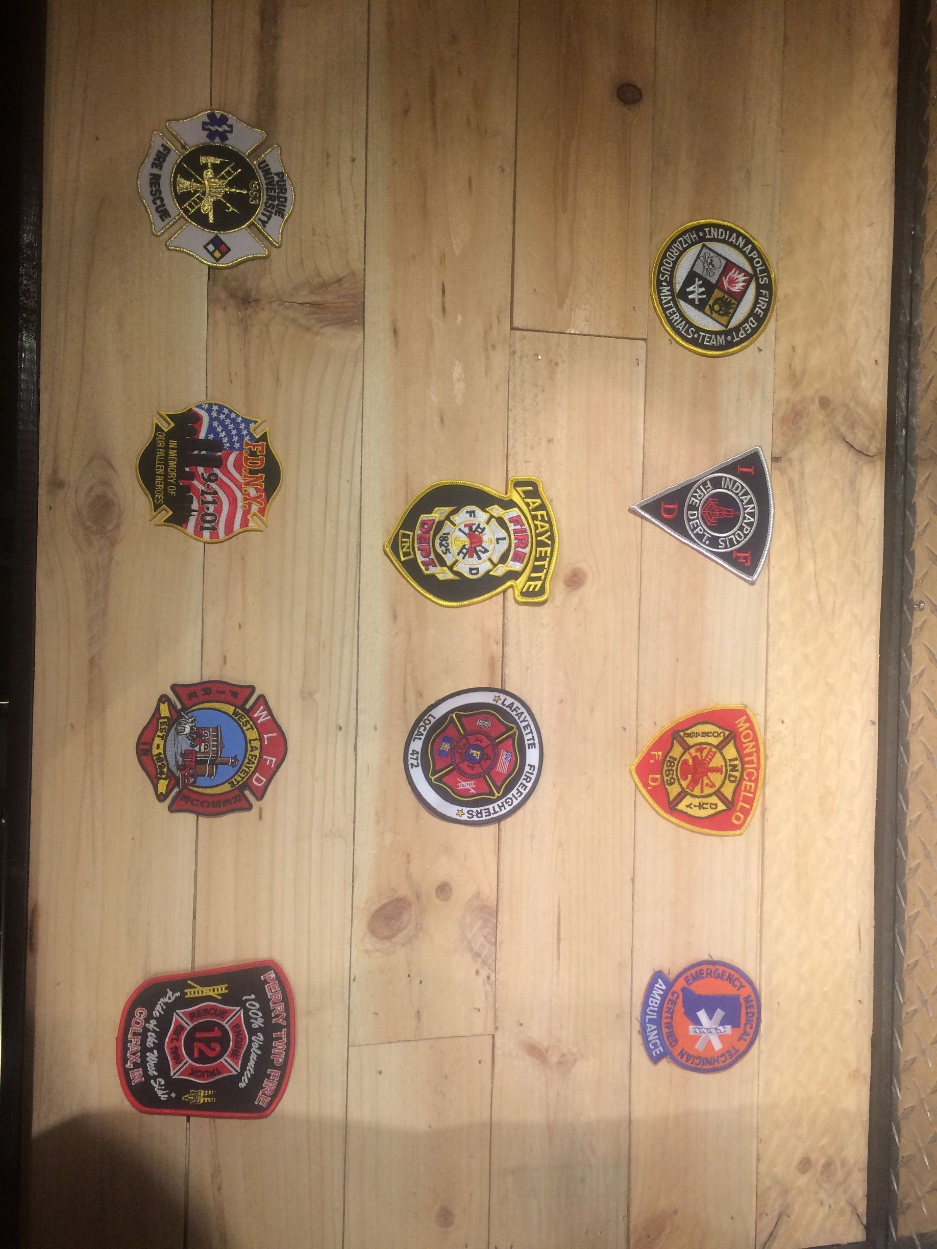 Eight colorful handmade beaded ornaments arranged on a wooden board.