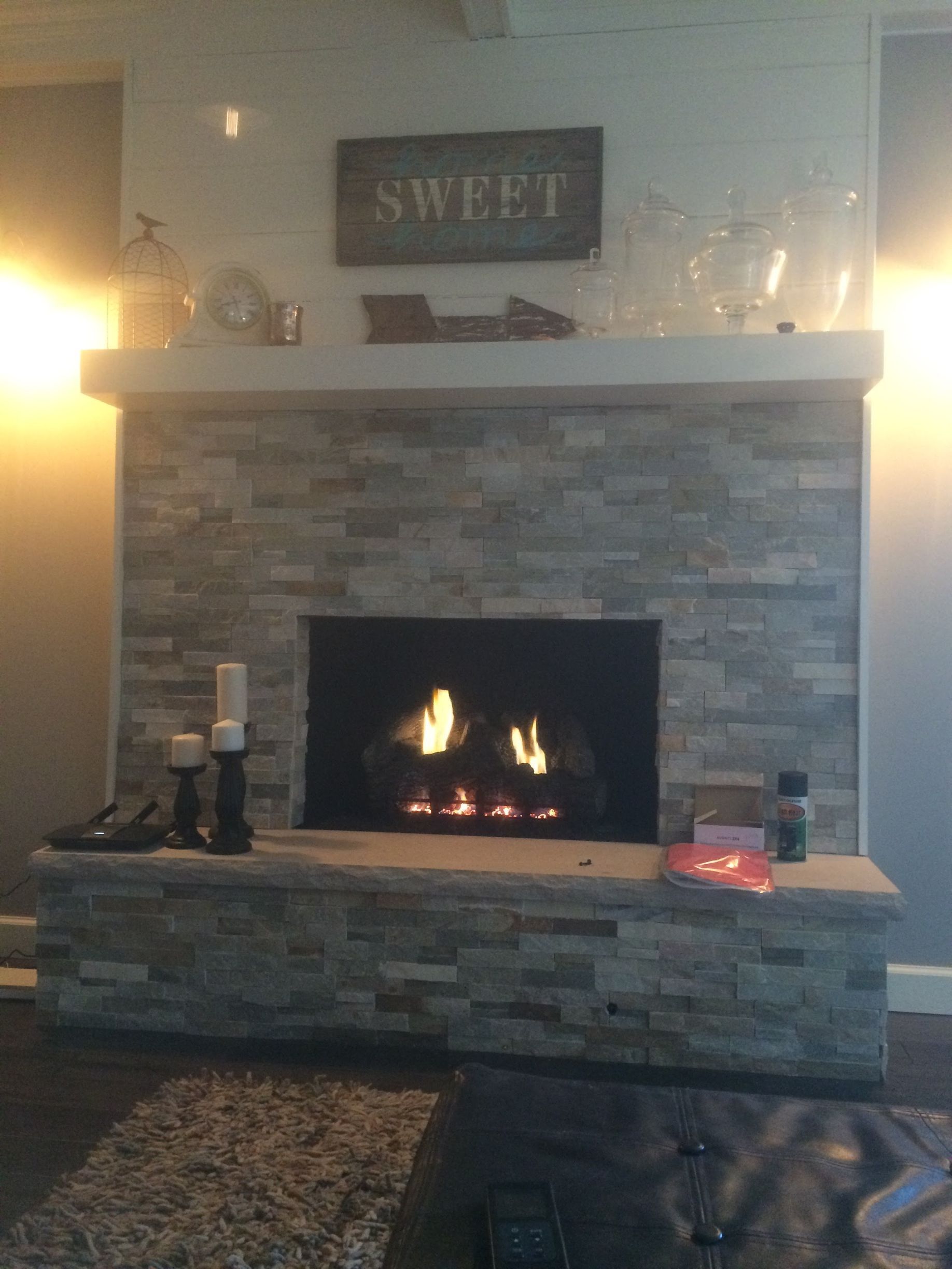 Stone fireplace with a lit fire, candles on the mantel, and a “SWEET” sign above.