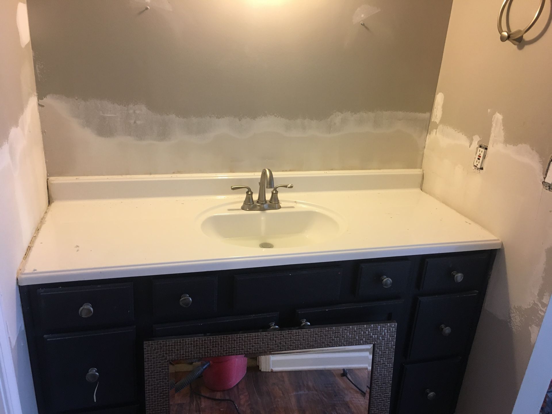 Bathroom vanity with white sink and black cabinets beneath a large mirror.