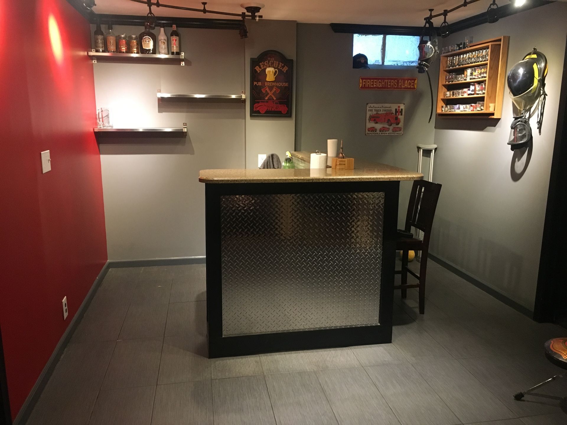 Small bar room with a central counter, red wall, shelves, and a wall-mounted phone.