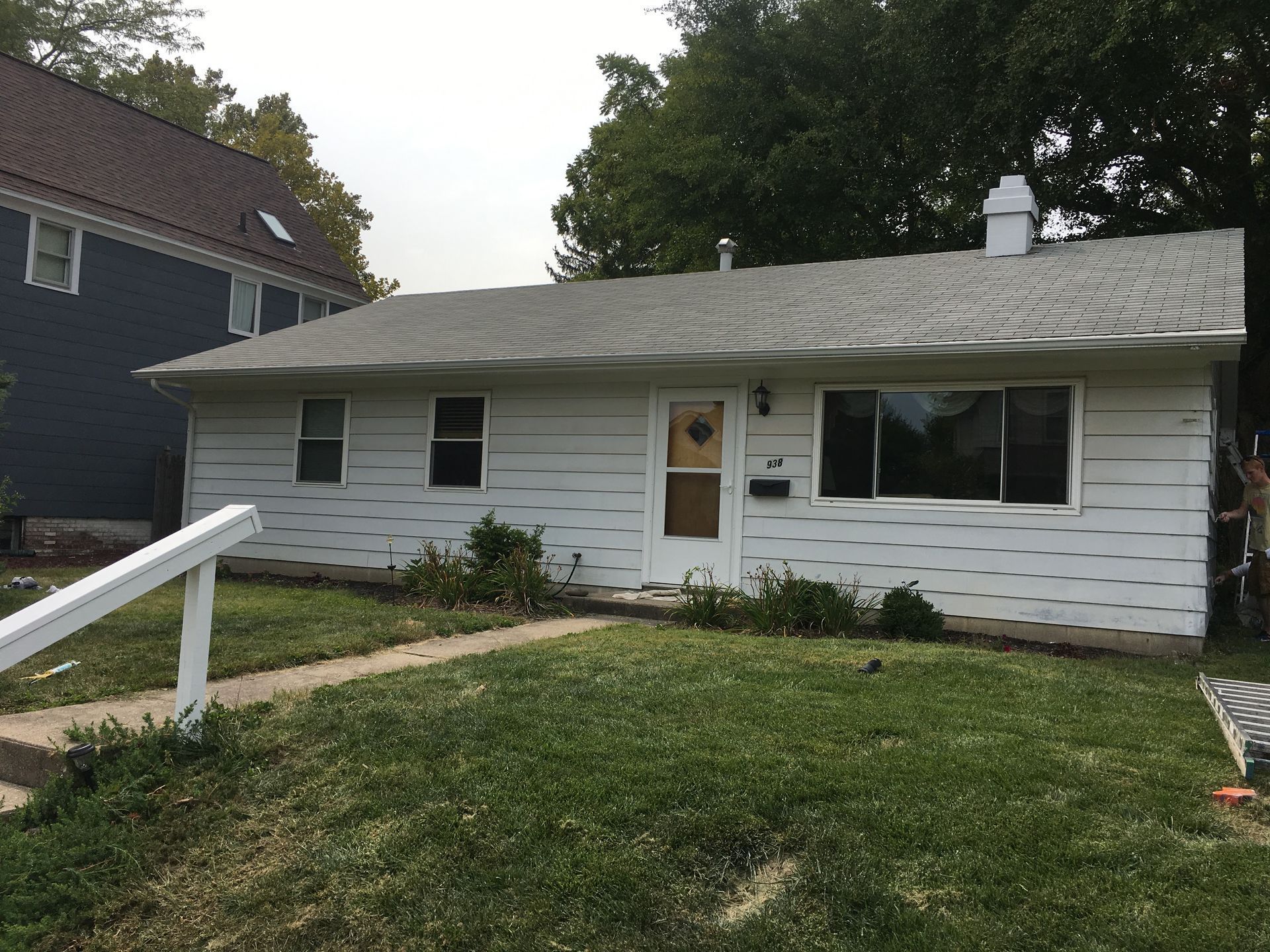 Small white single-story house with a front door, large windows, and a grassy yard