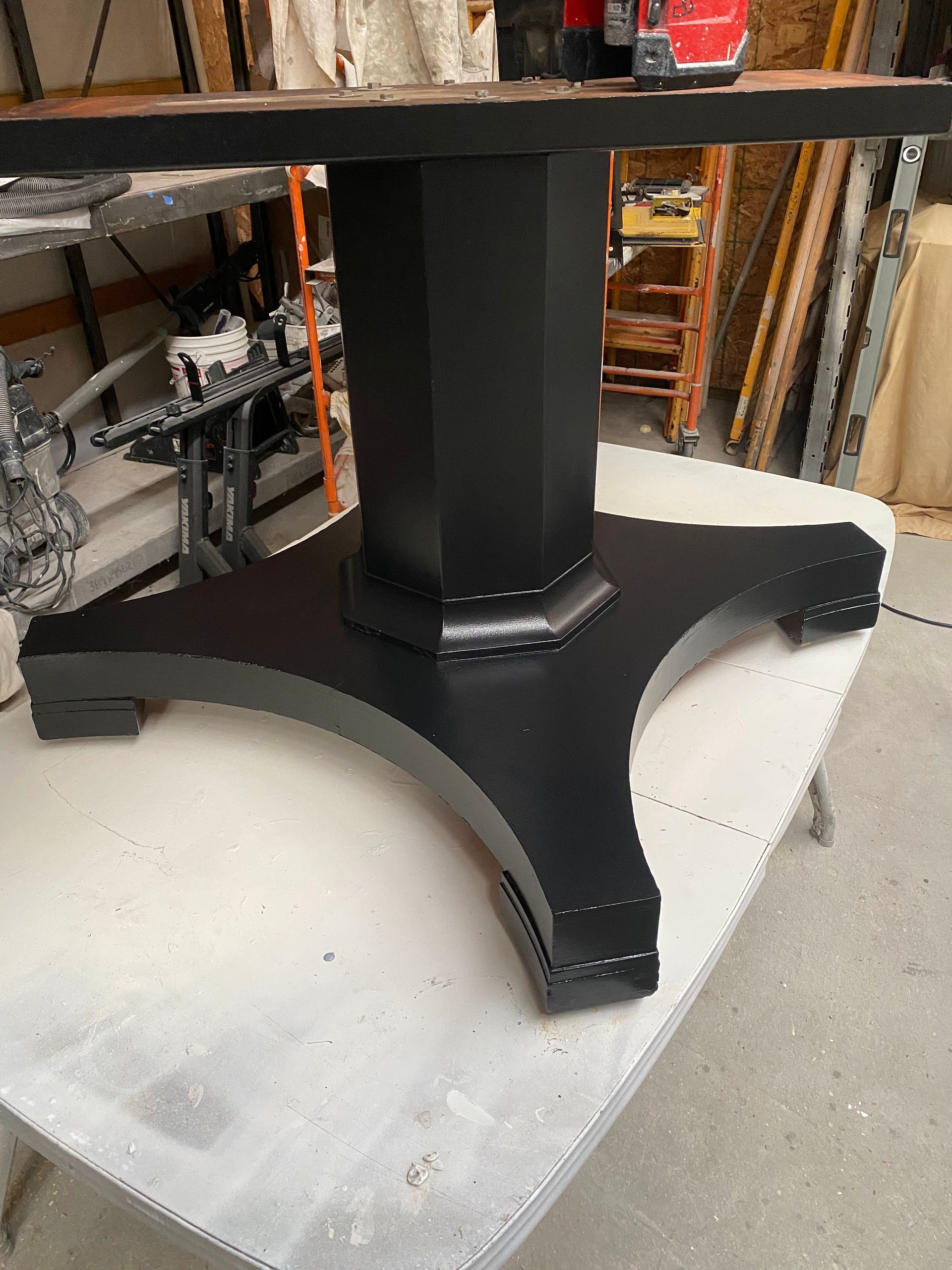 Black metal table base on a padded surface in a workshop or storage area