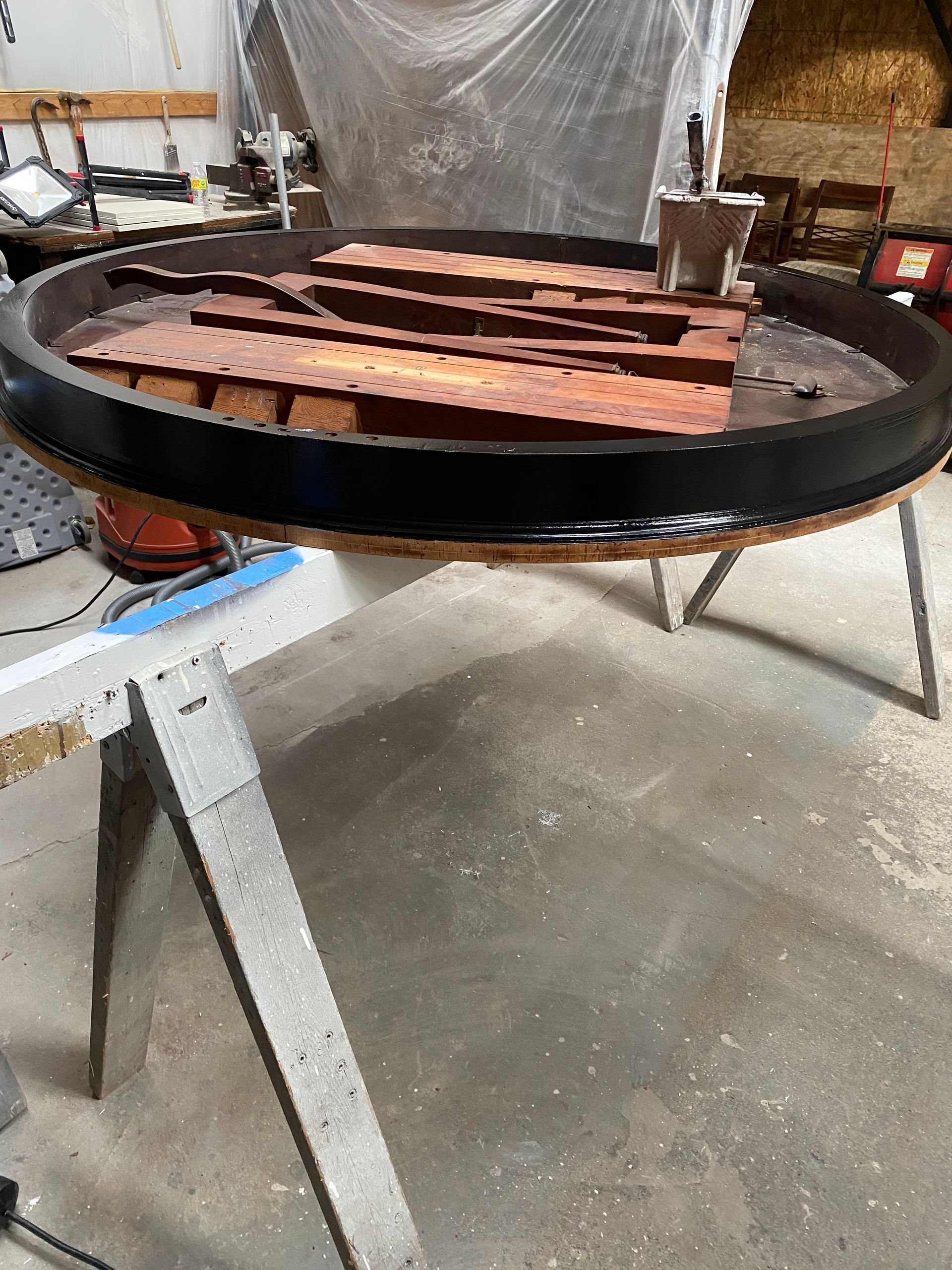 Rusting metal strips on a round black tray in a workshop, resting on a metal stand.