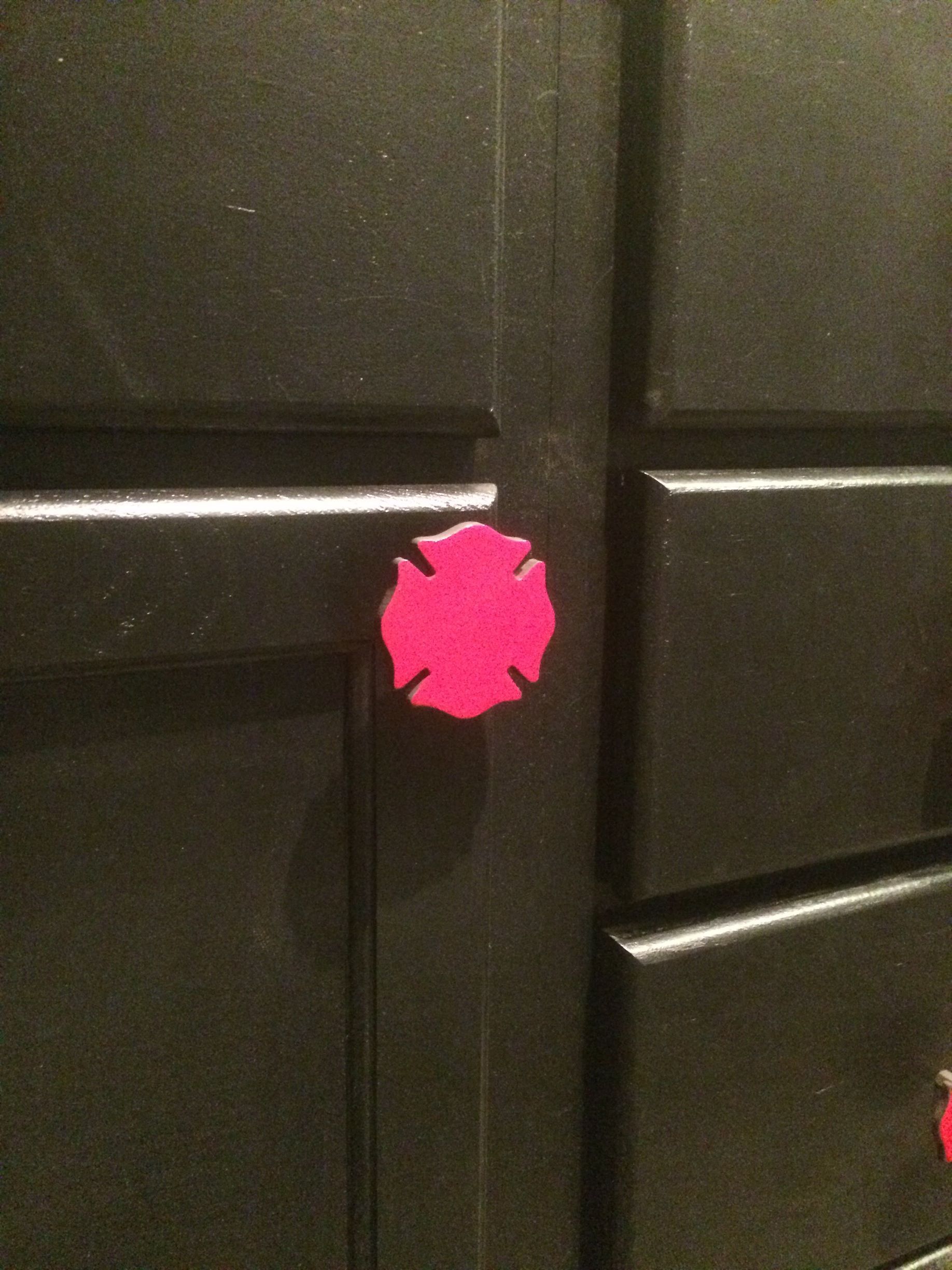 Black cabinet doors with a bright pink sticker or paint mark at the center seam.