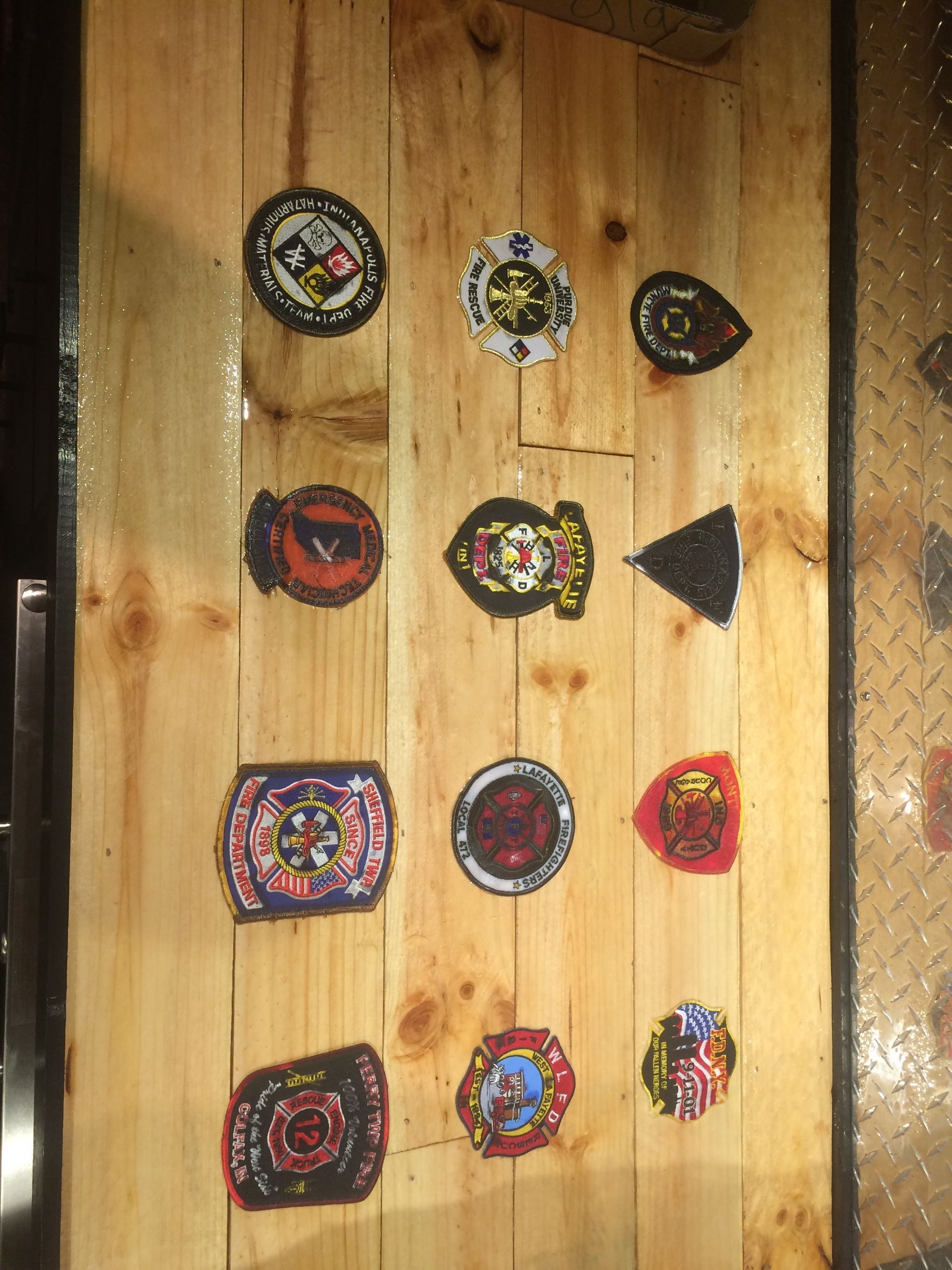 Colorful handmade pinback buttons and patches arranged in rows on a wooden board.