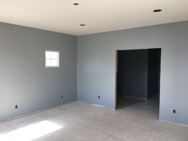Empty gray room with tiled floor, small window, recessed lights, and open doorway