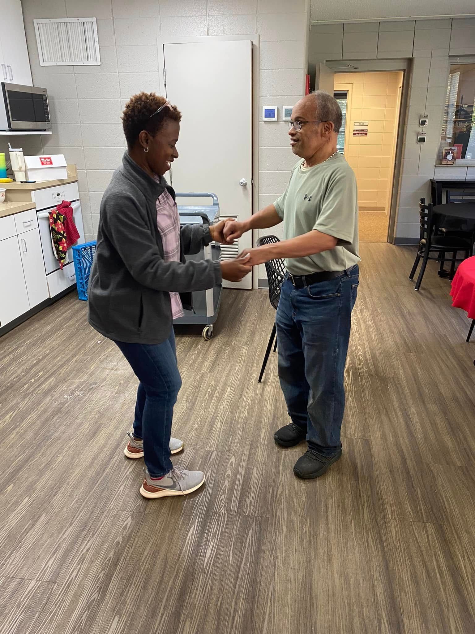 A man and a woman are dancing together in a kitchen.