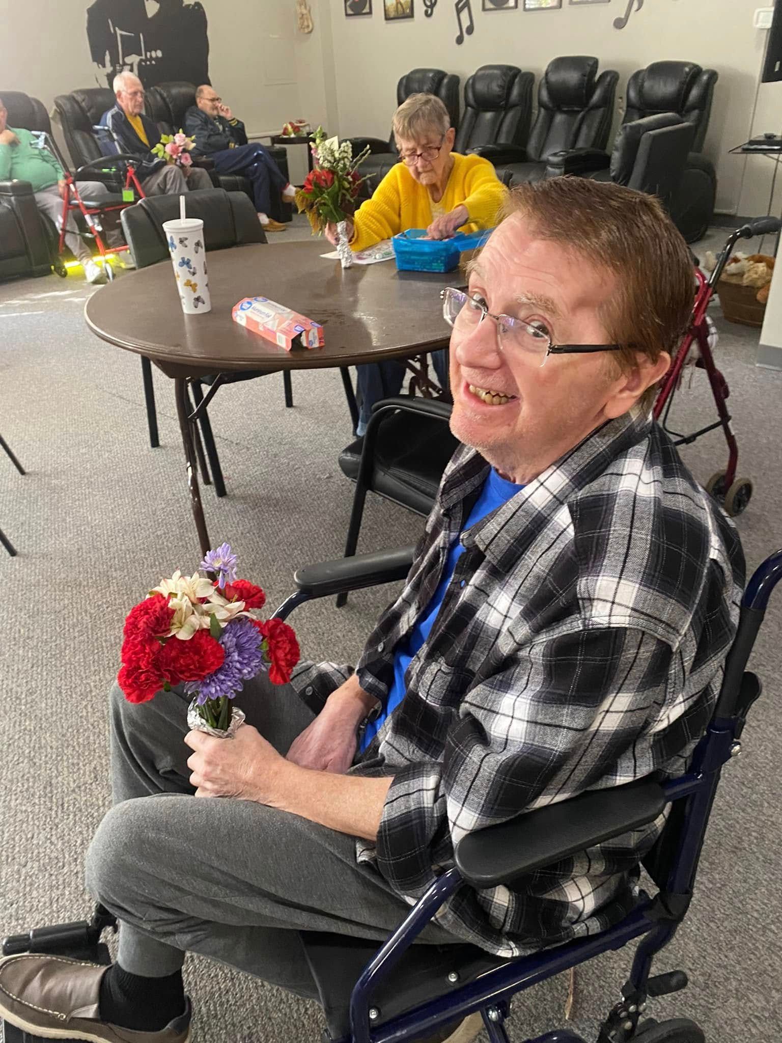 A man in a wheelchair is holding a bouquet of flowers.