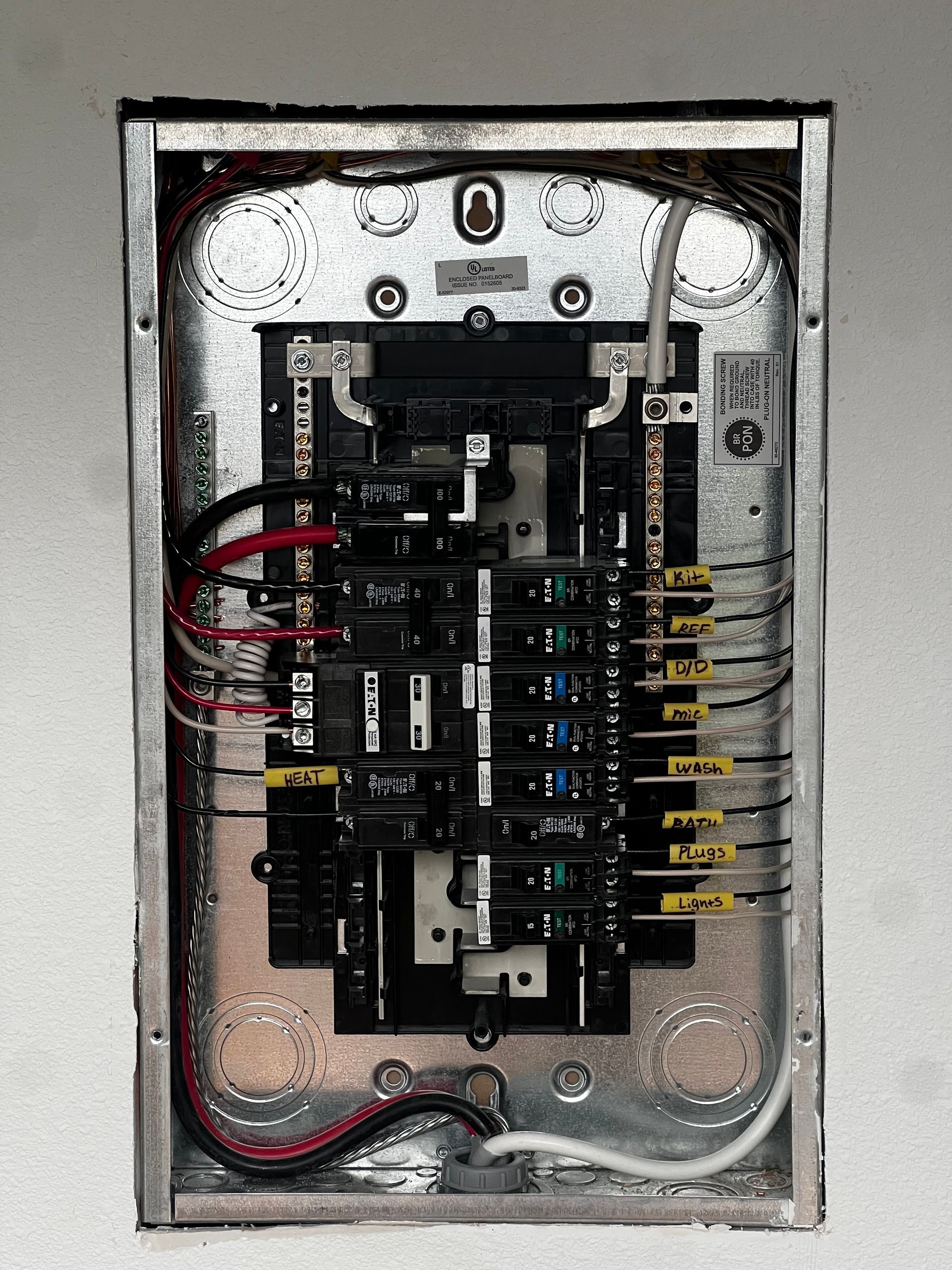 Open electrical breaker panel with wires and multiple circuit breakers inside a metal box