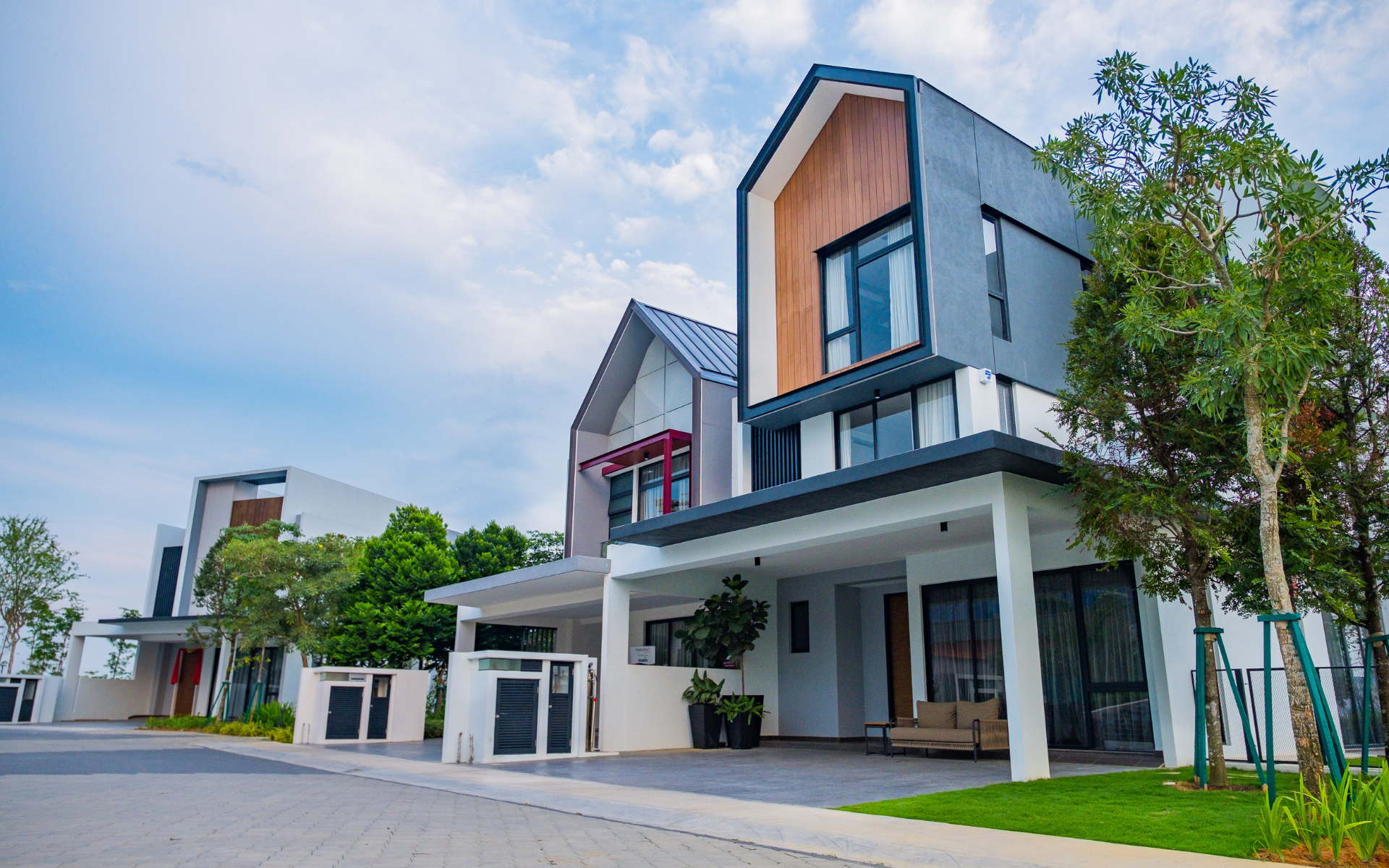 Modern houses with angled roofs and wood accents under a bright blue sky.