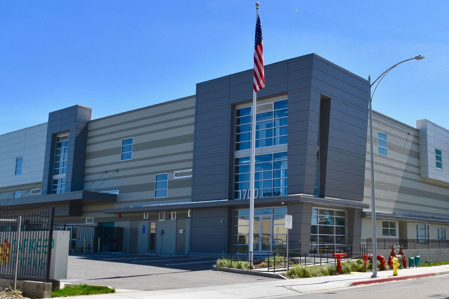 Modern building with flag, blue sky. Grey and white facade.