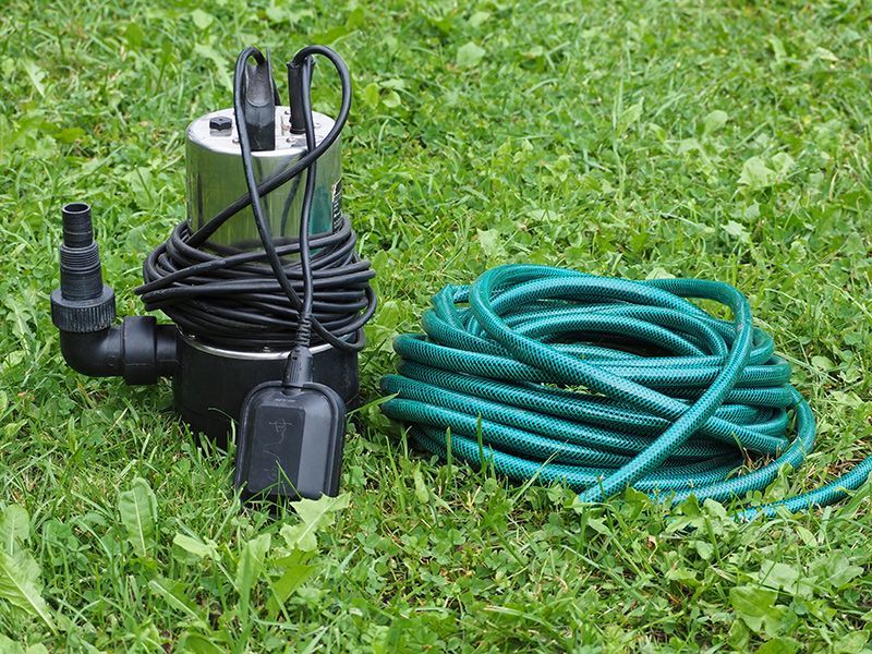 A water pump and hose are sitting on the grass.