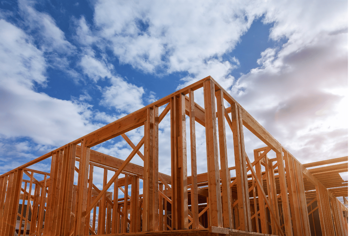 Wood-framed house under construction against a partly cloudy blue sky