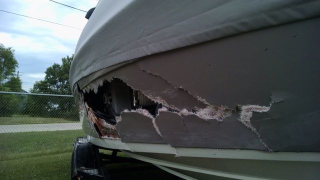 Damaged gray tarp on a trailer with a large tear, showing the trailer’s side underneath.