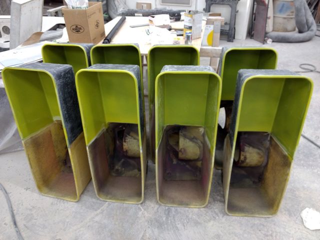 Four lime-green rectangular industrial bins or ducts stacked outdoors on a concrete floor.