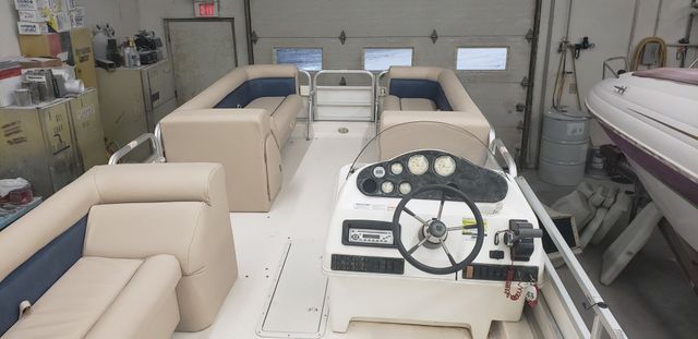 Pontoon boat with beige seats and steering console inside a boat storage garage