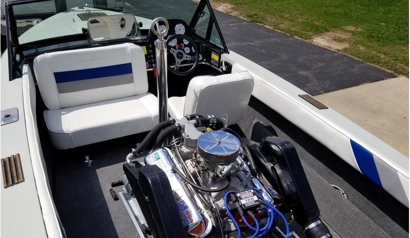 Open motorboat with white and blue seats and a shiny engine on the deck