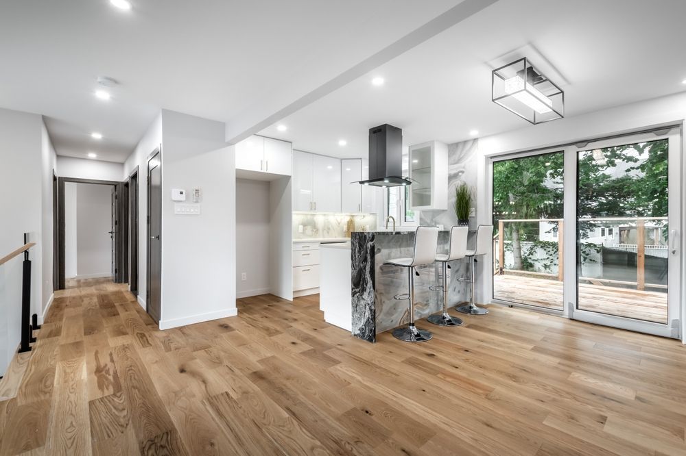 Modern kitchen and living space with wood floors, white cabinets, and large sliding doors.
