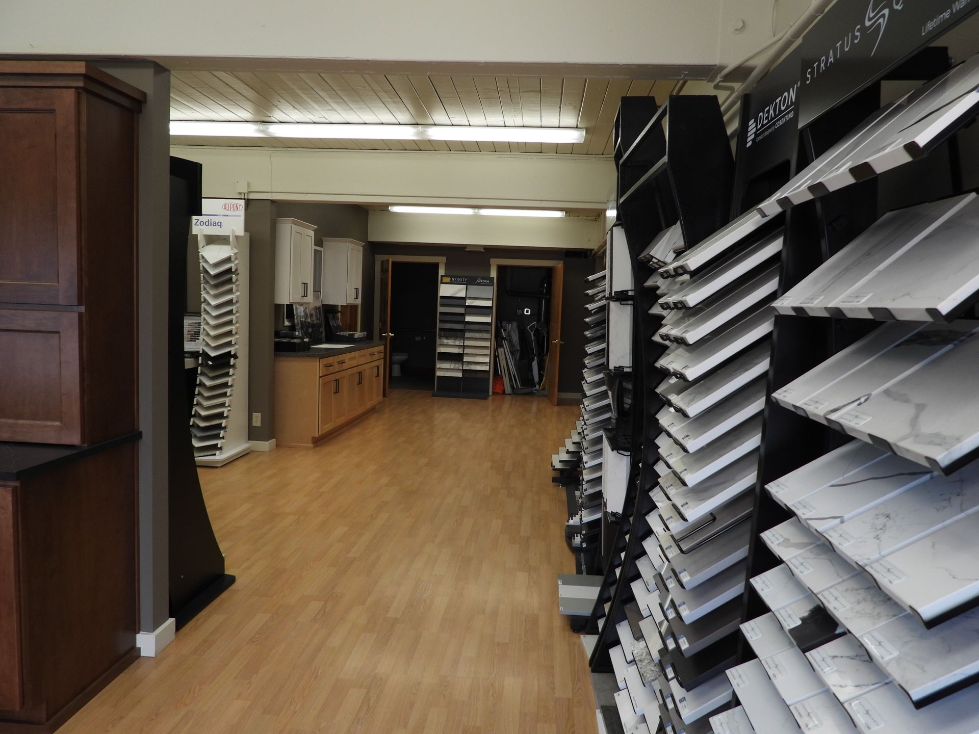 Office file room with shelves of paper trays and cabinets along a wood floor corridor