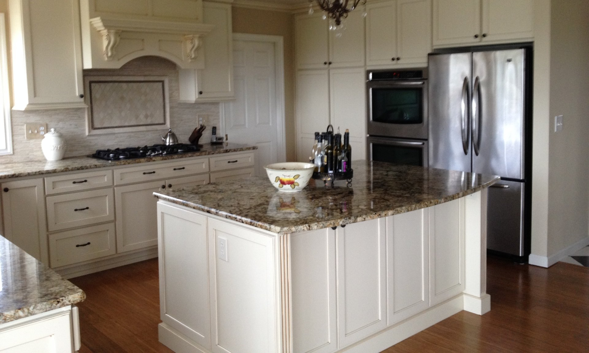 Bright modern kitchen with white cabinets, granite island, and stainless steel refrigerator