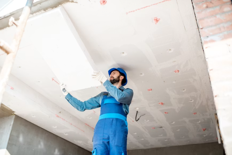 Worker sanding and smoothing ceiling drywall joints inside a room during work by a drywall contractor in Ahwatukee, AZ