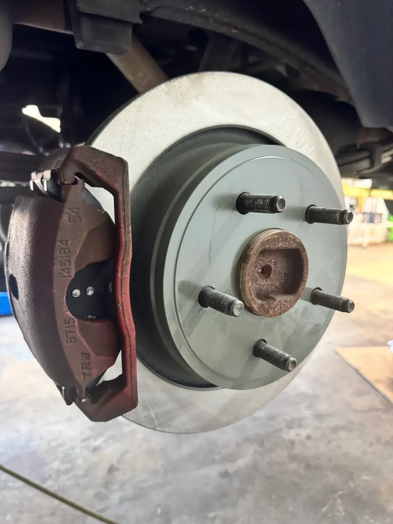 Car brake rotor and caliper, close-up under a vehicle on a lift | RMP Auto