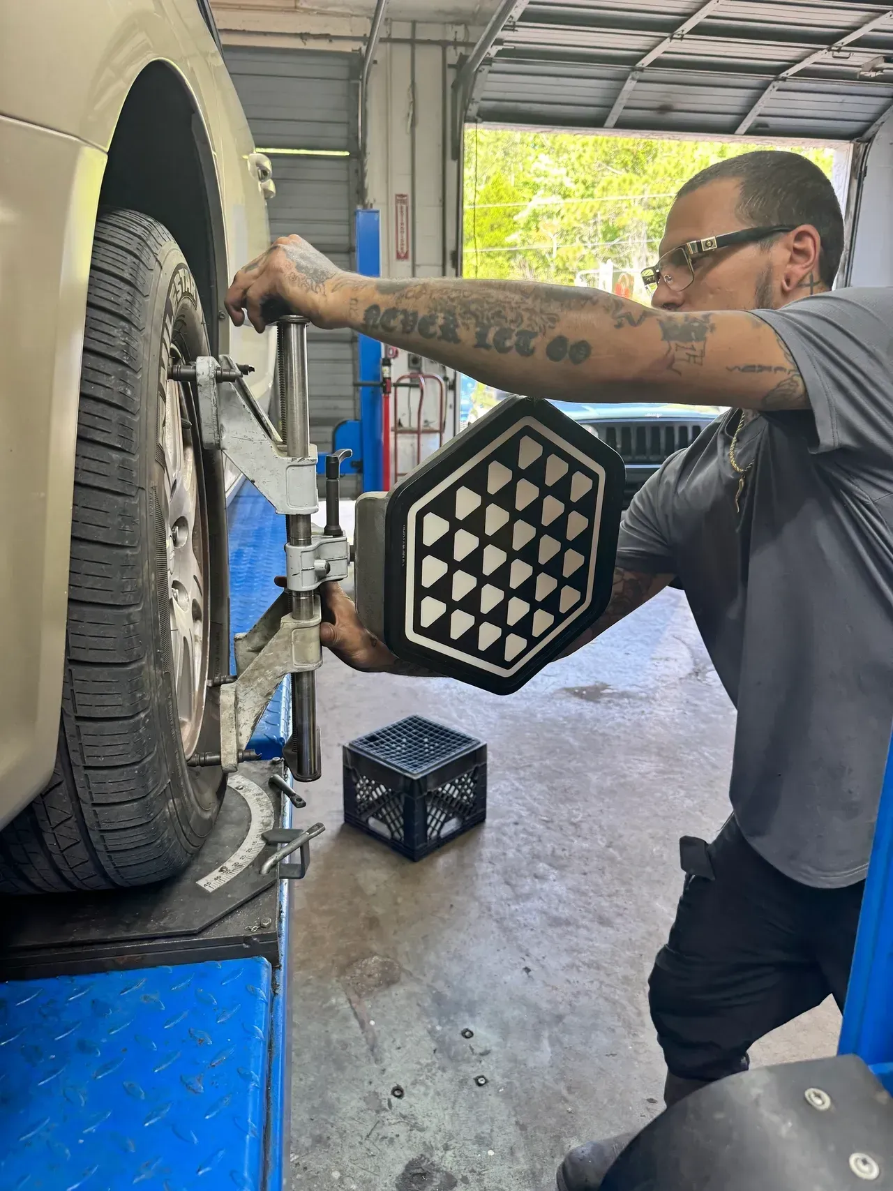 Mechanic aligning a car tire on a lift in an auto shop | RMP Auto