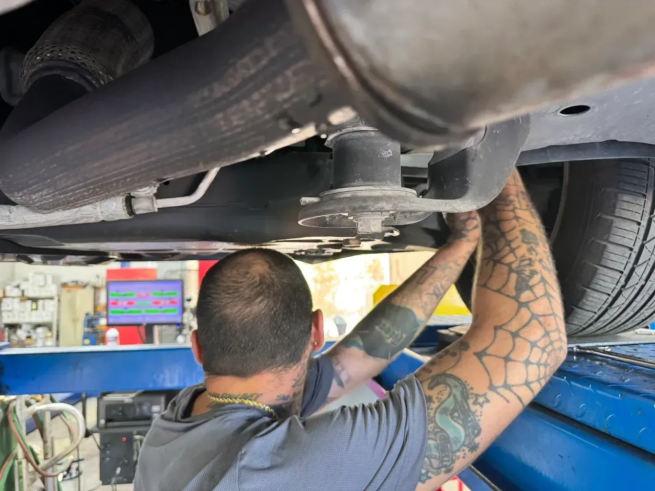Mechanic working under a car on a lift in an auto repair shop | RMP Auto