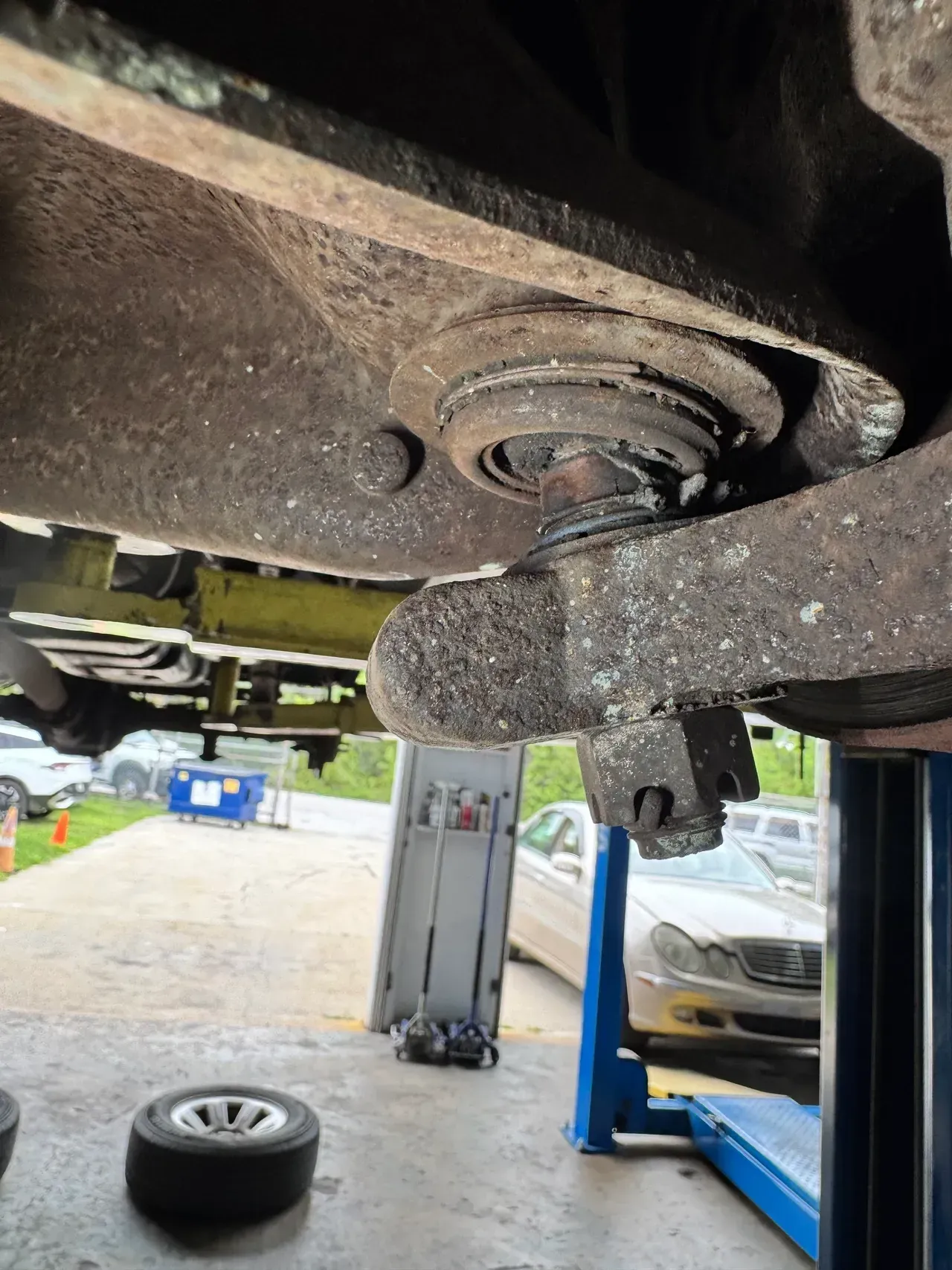 Undercarriage of a car on a lift in a garage, showing a wheel hub and nearby tools. | RMP Auto