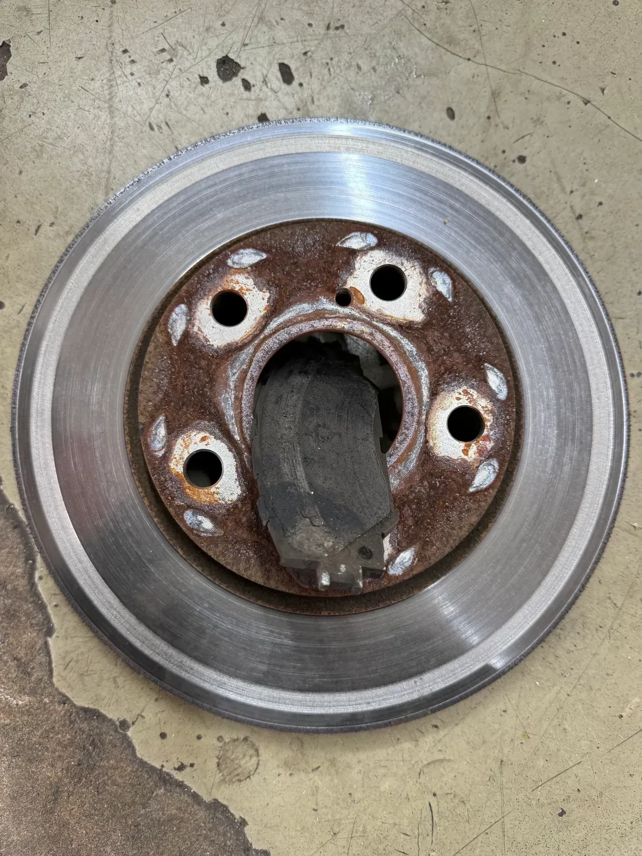 Rusty car brake rotor with wheel hub on a concrete floor | RMP Auto