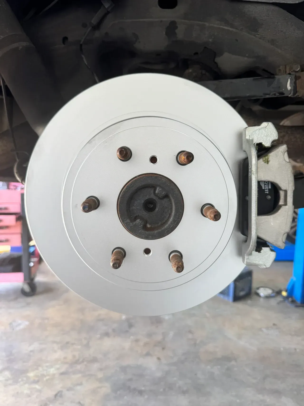 Car wheel with silver brake disc and caliper in a garage, viewed from the front | RMP Auto