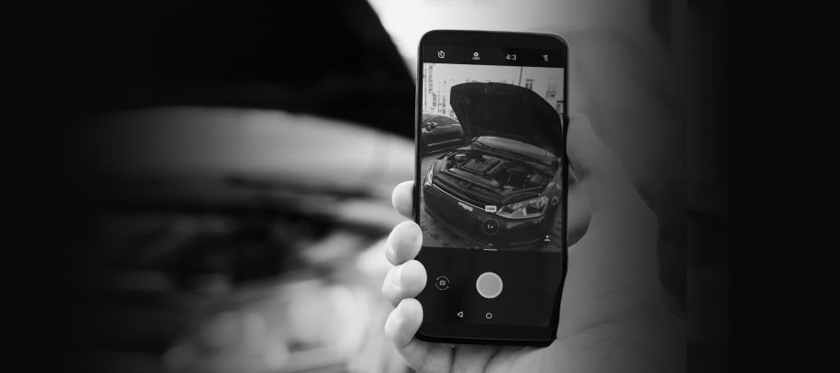 Person holding a smartphone showing a car engine with the hood open on screen | RMP Auto