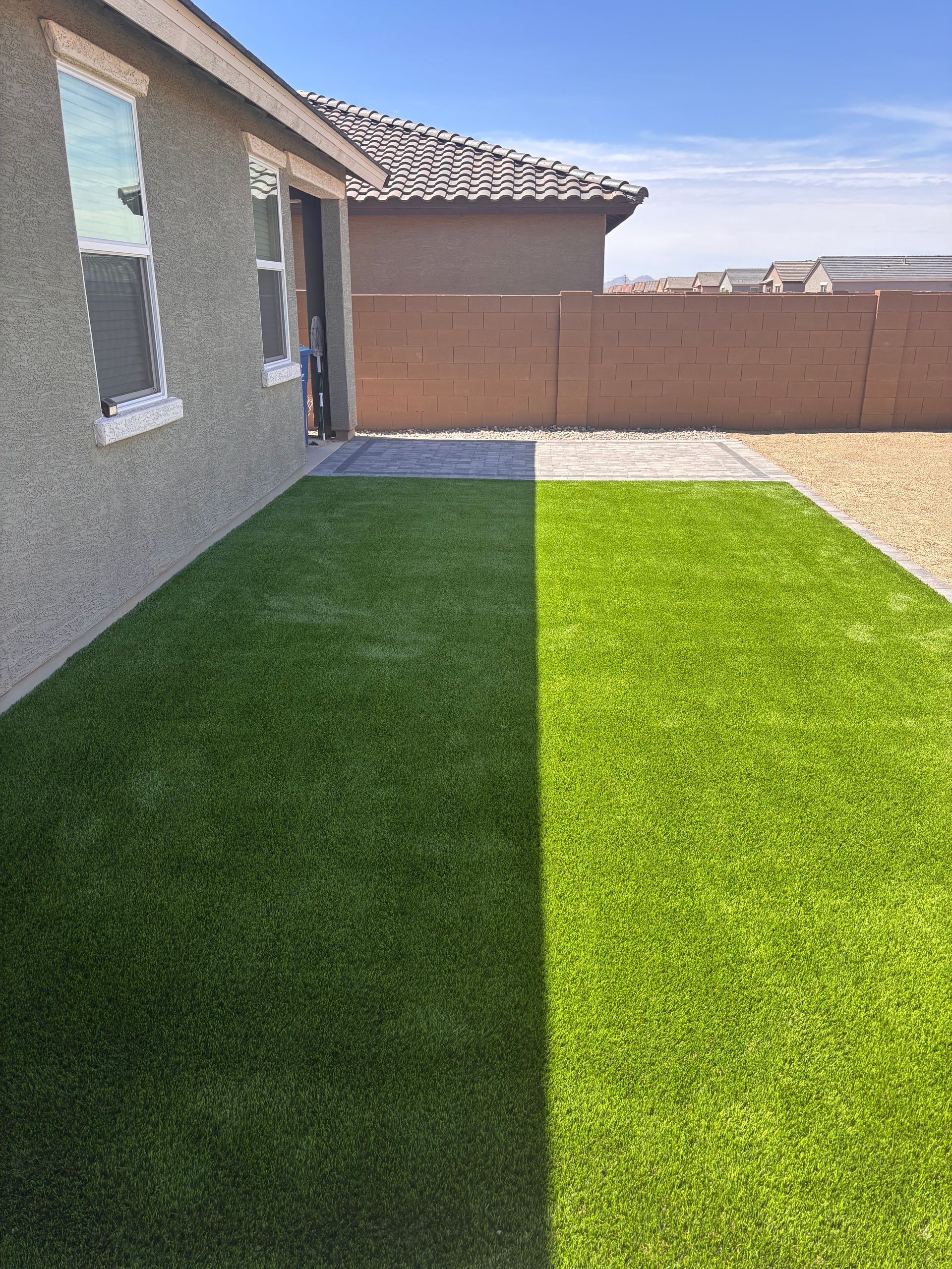 Backyard with artificial turf and a patio, sunny day.