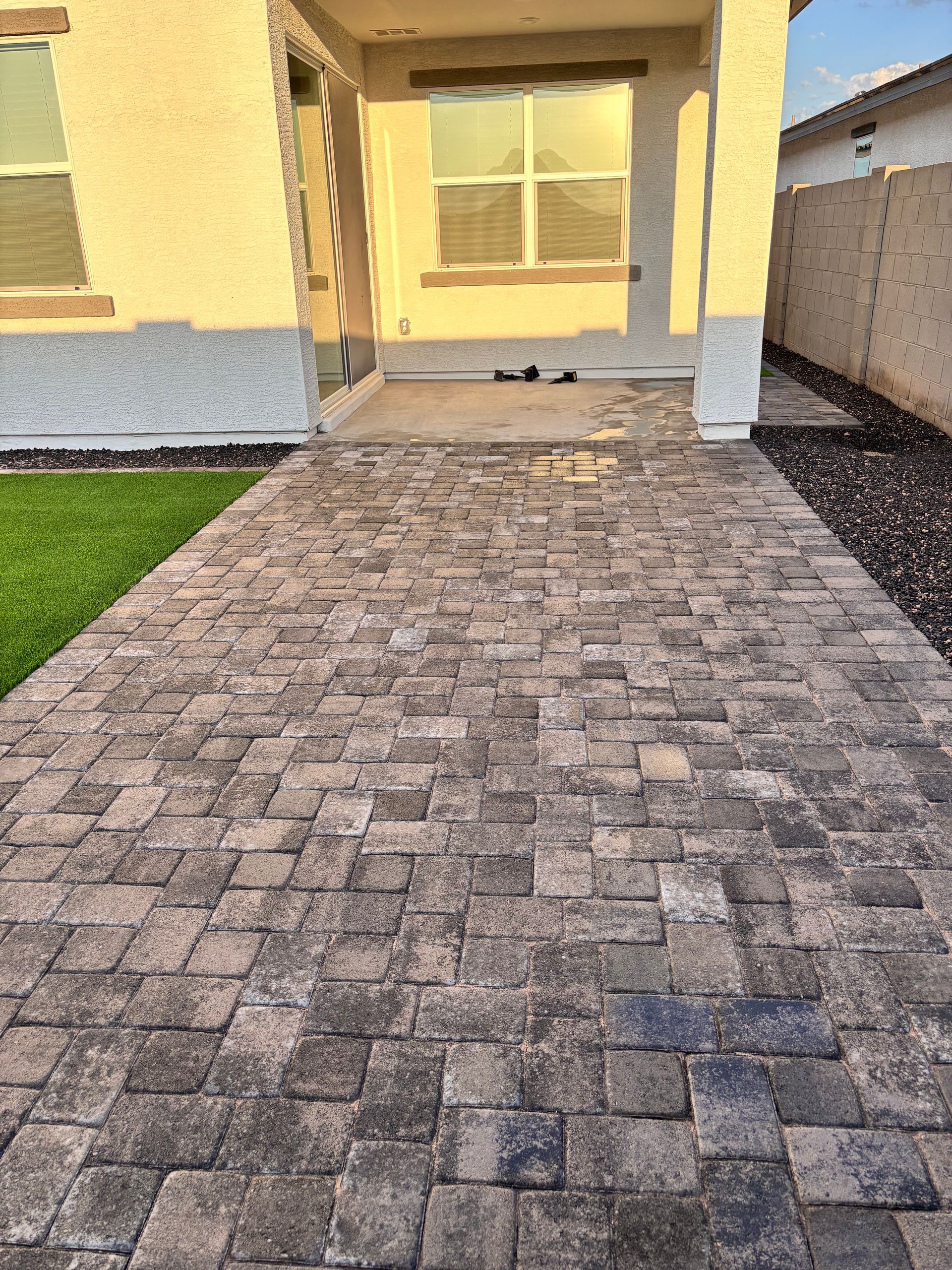 Brick walkway leading to a house entrance with a covered porch.