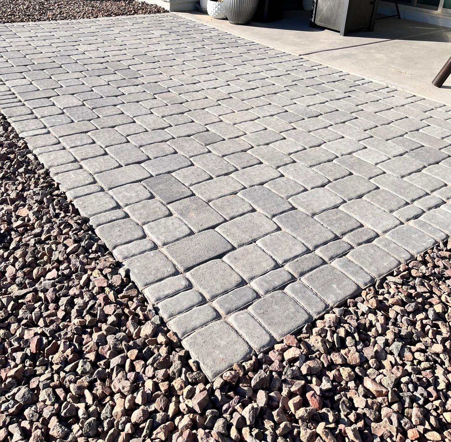 A brick walkway with gravel on the side of it.