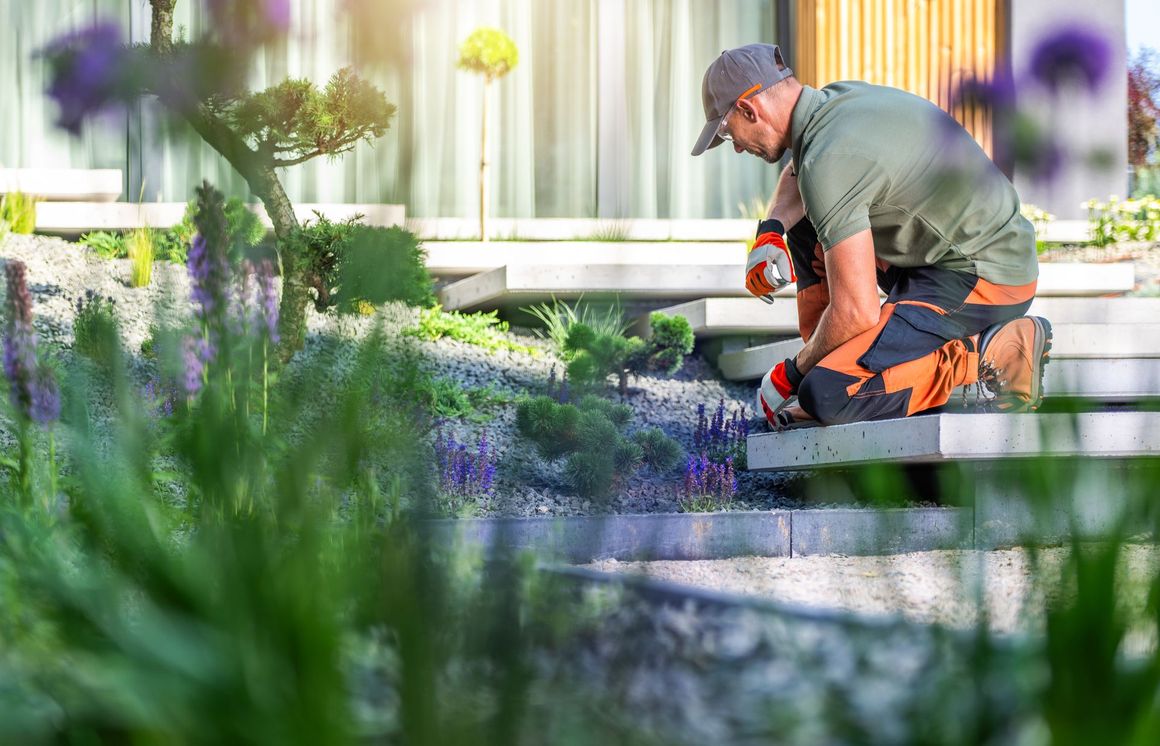 A man is kneeling down in a garden.