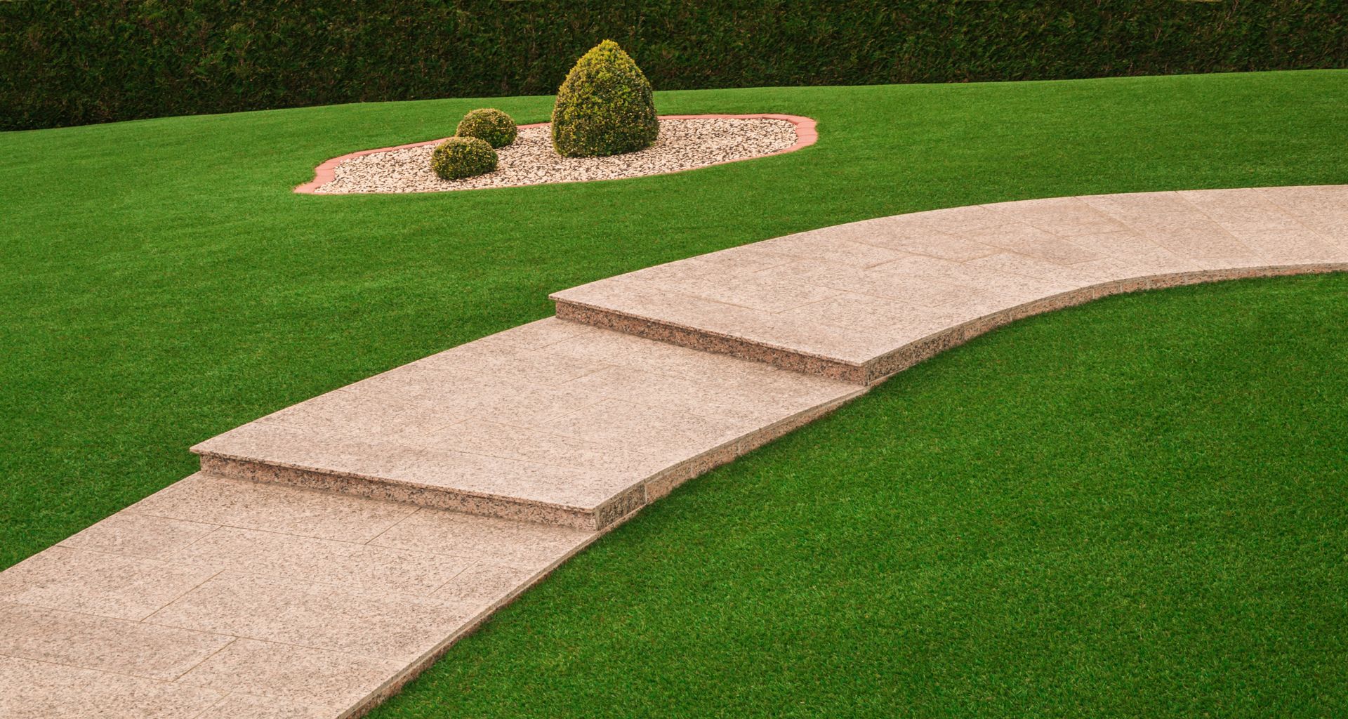 A stone walkway going through a lush green lawn.
