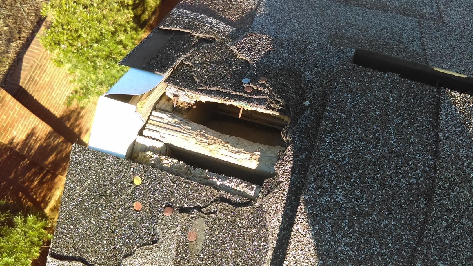 Damaged shingle roof with a broken vent opening and exposed wood near the edge