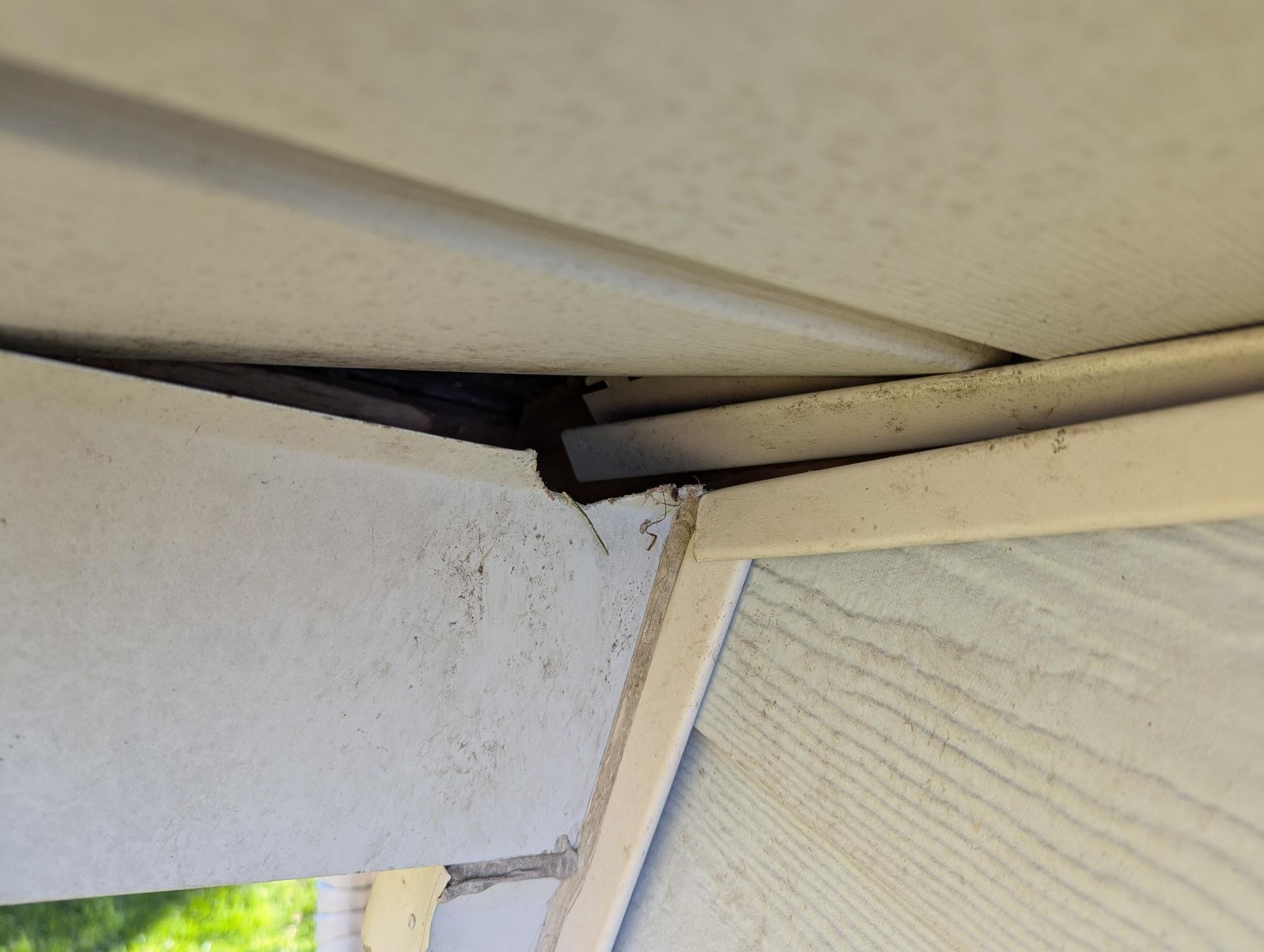 Close-up of a damaged roof and wall corner with a visible gap and cracked trim.