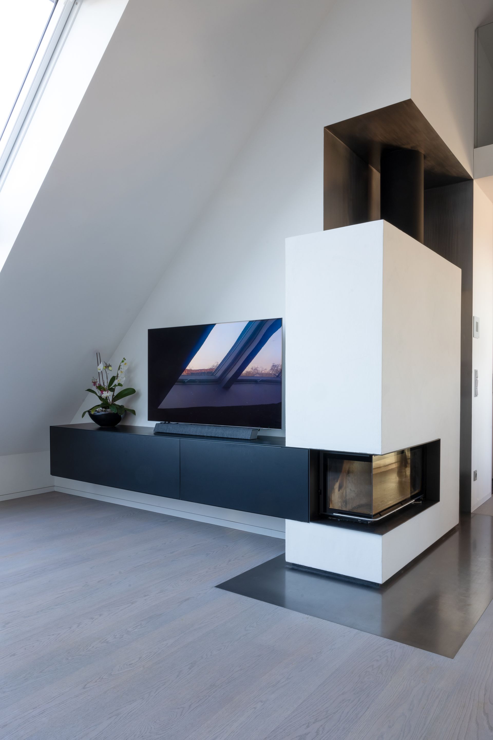 Modernes Wohnzimmer mit Kamin, Fernseher vor einer weißen, schrägen Wand.Fotograf Tübingen. Fotograf Reutlingen.