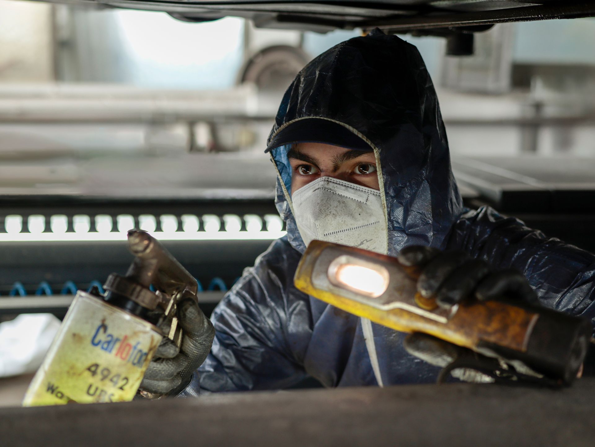 Eine Person in Schutzkleidung untersucht  die Unterseite des Fahrzeugs.Fotograf Tübingen. Fotograf Reutlingen.