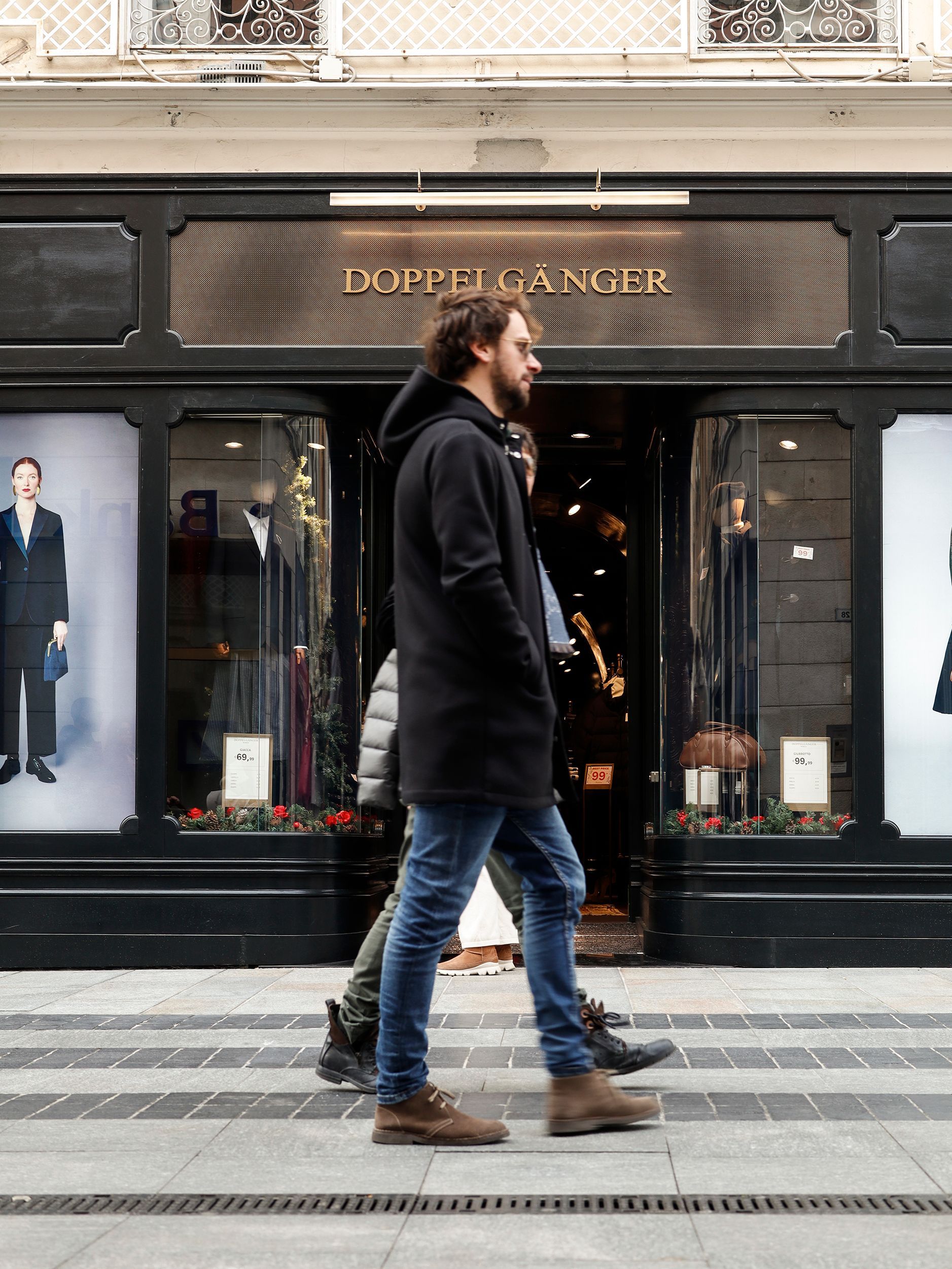 Ein Mann geht an einer Boutique mit dunkler Fassade vorbei.Fotograf Tübingen. Fotograf Reutlingen.