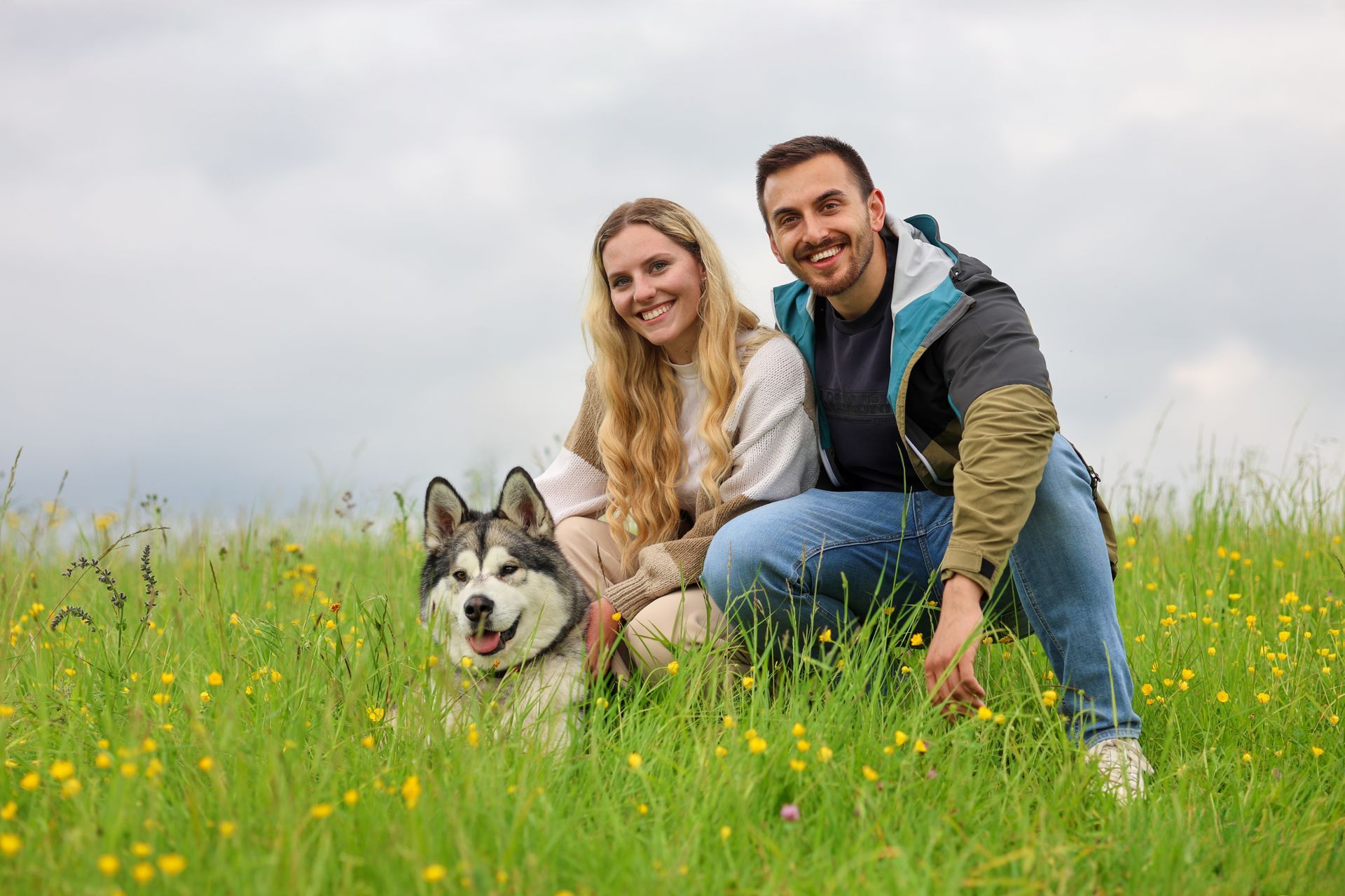 Ein Paar und sein Husky in einer gelben Blumenwiese; sie lächeln in die Kamera. Fotograf Tübingen. Fotograf Reutlingen.