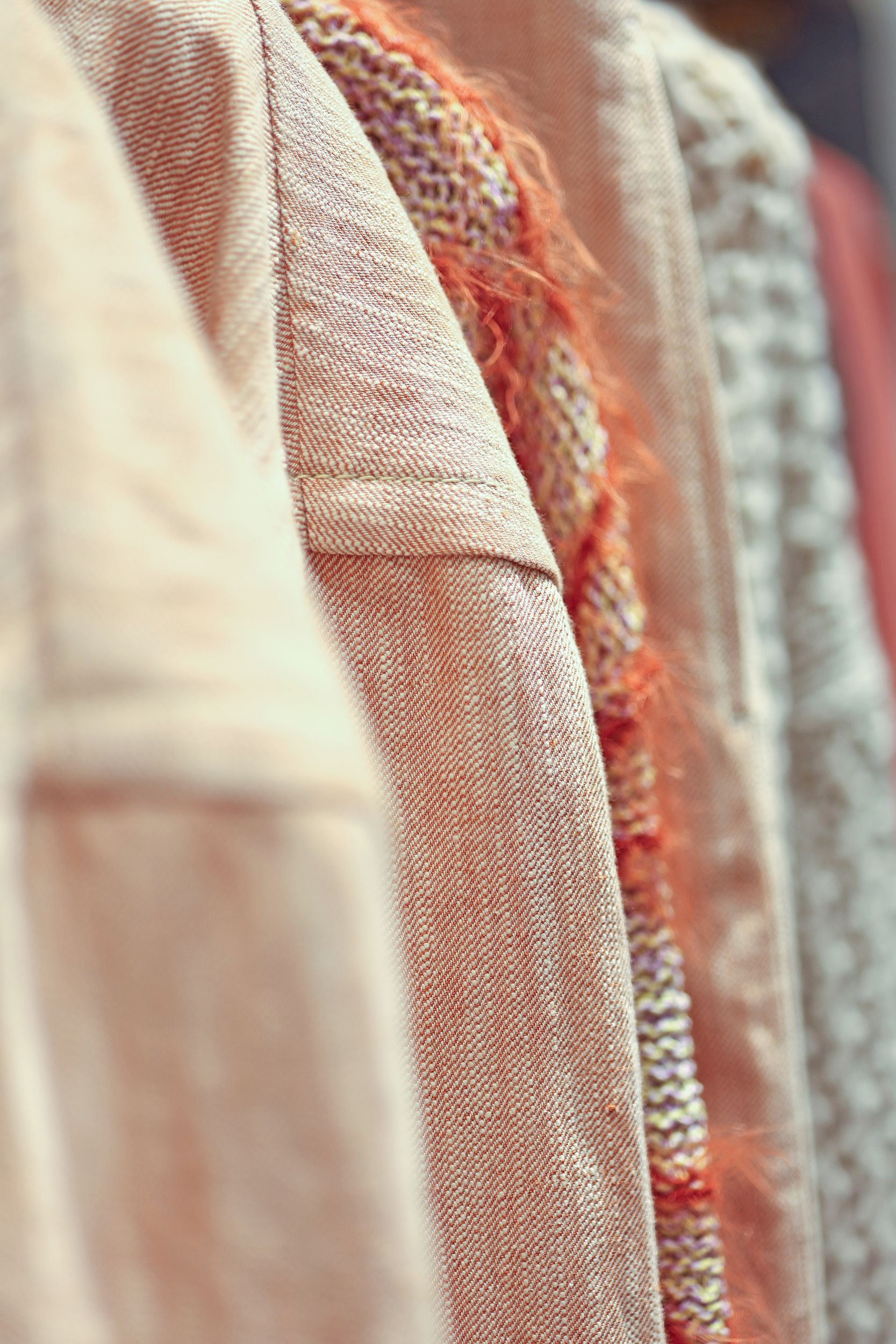 Nahaufnahme von hängender Kleidung: beige, pfirsichfarbene und orangefarbene Pullover.Fotograf Tübingen. Fotograf Reutlingen.