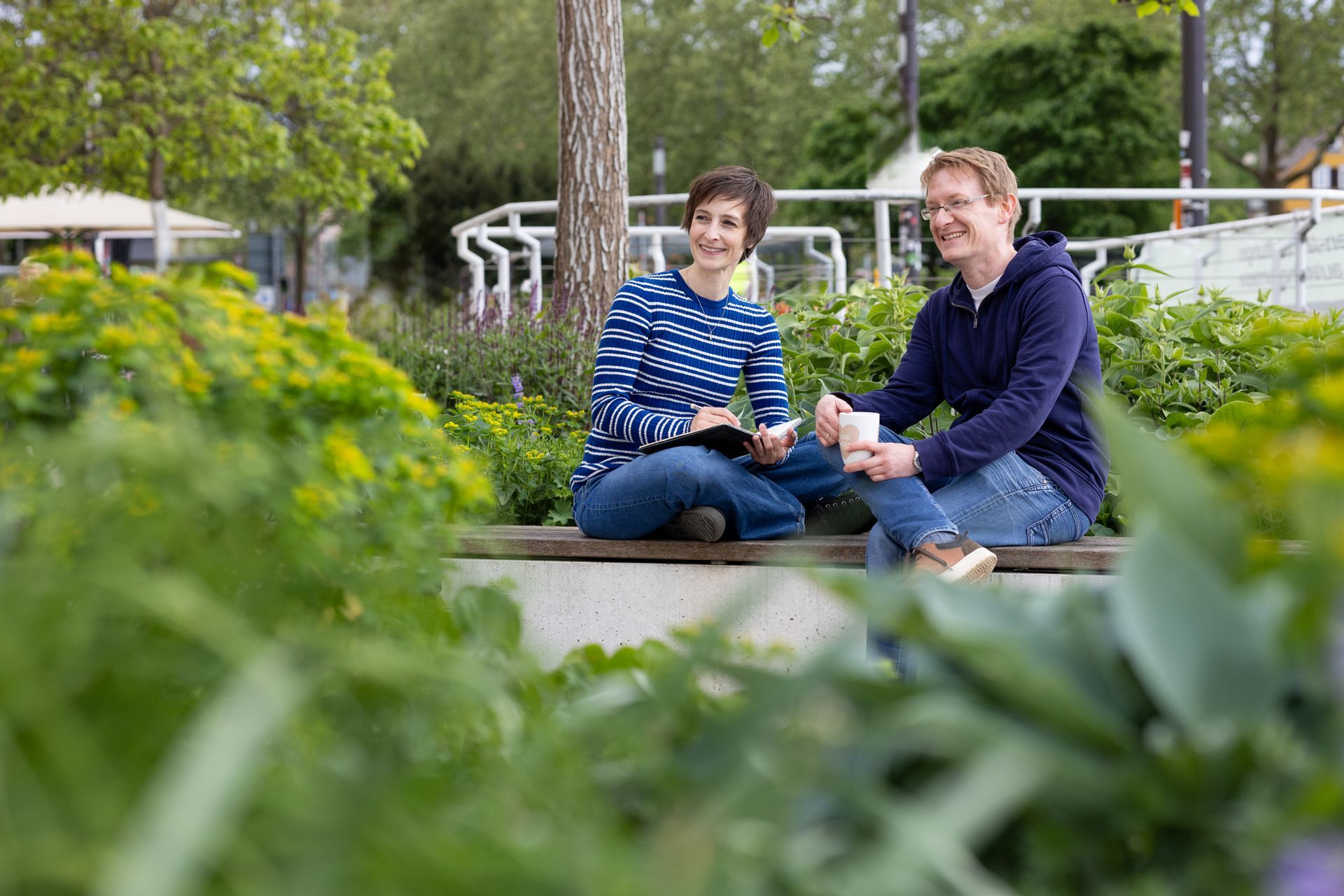 Zwei Personen sitzen lächelnd auf einer Bank in einem Garten und unterhalten sich.Fotograf Tübingen. Fotograf Reutlingen.