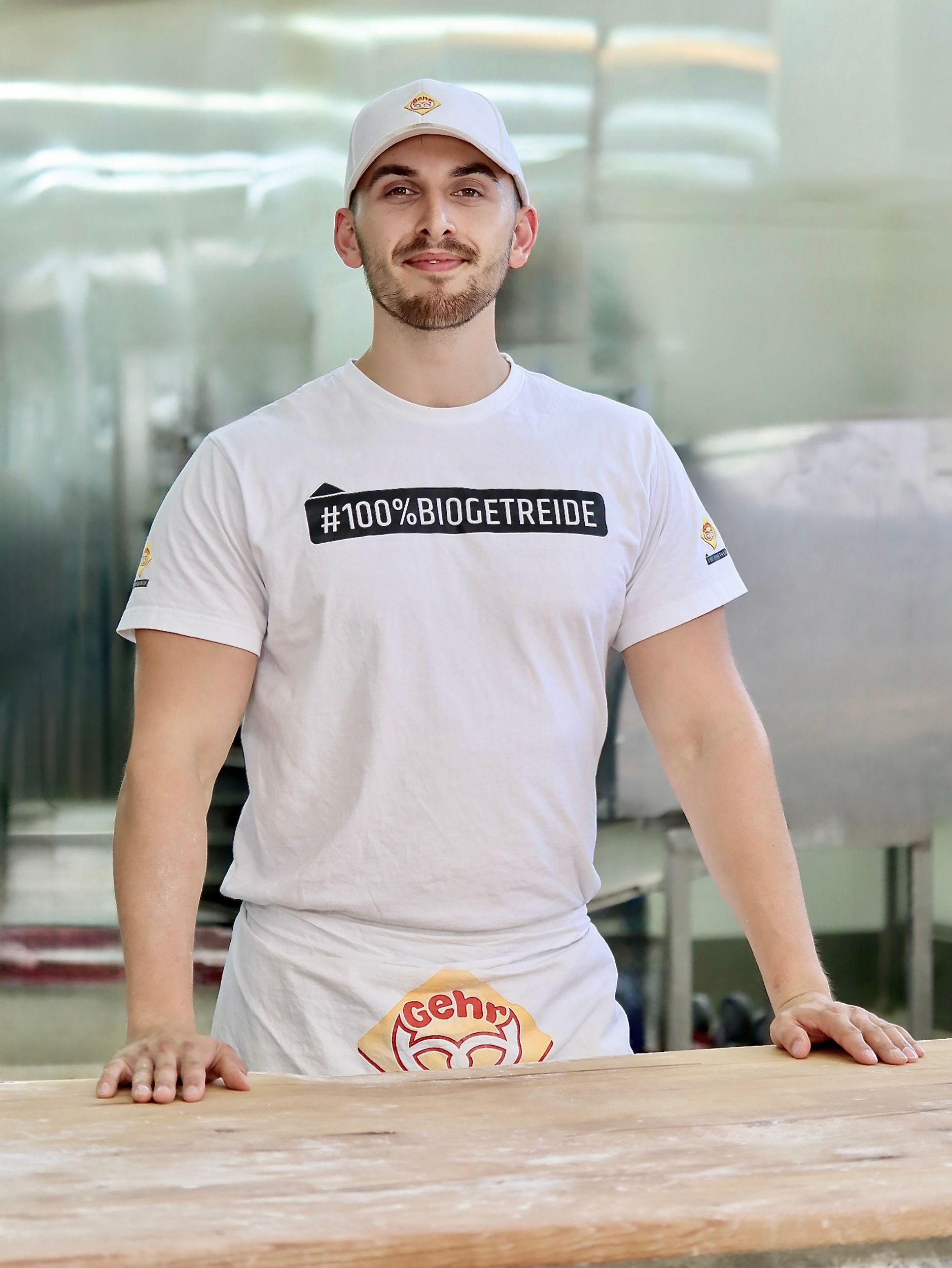 Ein Mann in Bäckeruniform lächelt. Auf seinem Hemd und seiner Schürze ist ein Logo.Fotograf Tübingen. Fotograf Reutlingen.