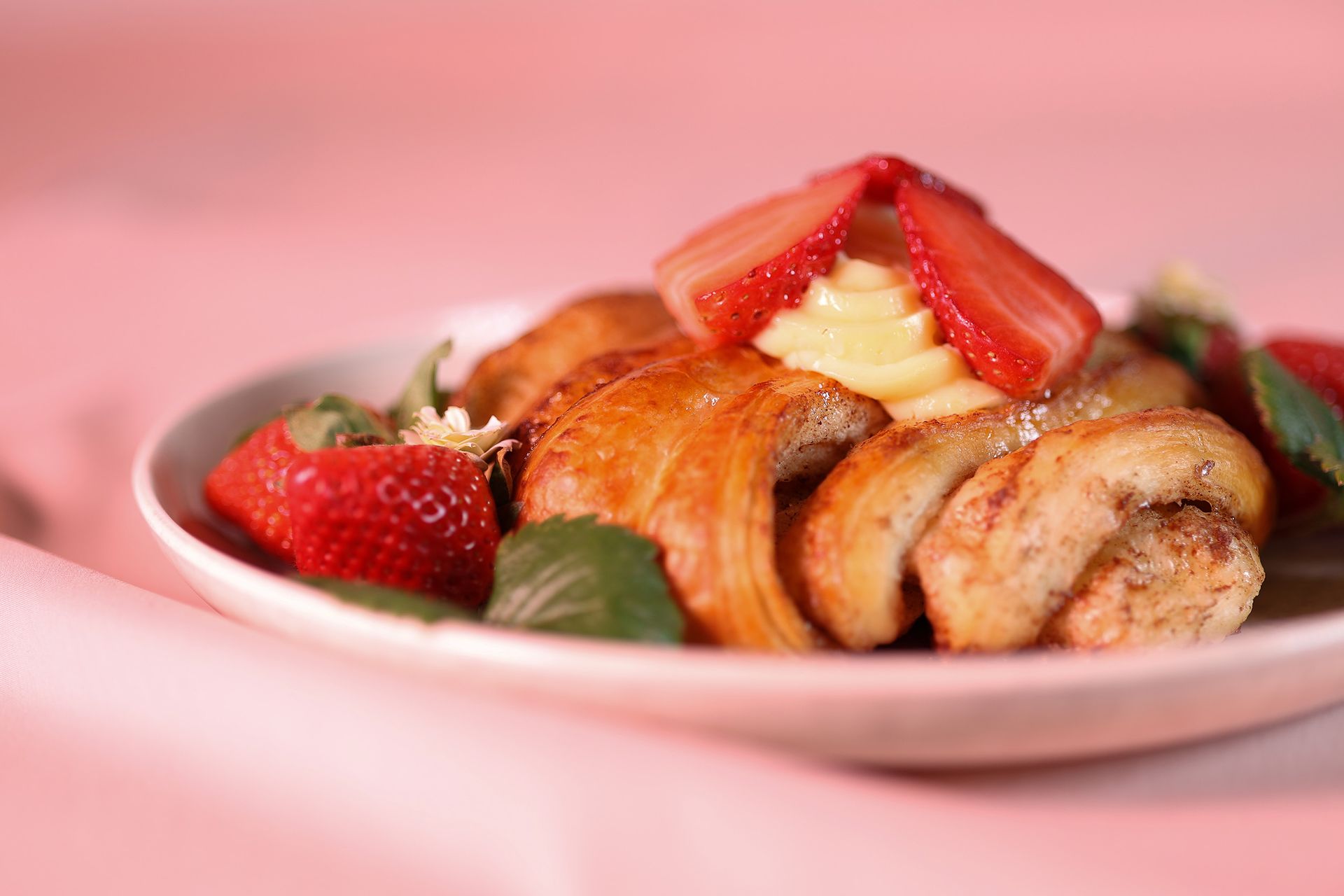 Franzbrötchen mit Pudding und Erdbeeren auf einem weißen Teller, rosa Hintergrund.Fotograf Tübingen. Fotograf Reutlingen.
